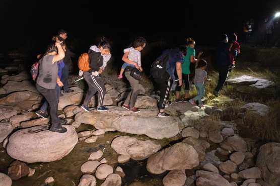 Migrantes caminan desde la orilla del Río Grande después de ser contrabandeados a través de la frontera entre Estados Unidos y México en Roma, Texas. (Foto Prensa Libre: AFP)