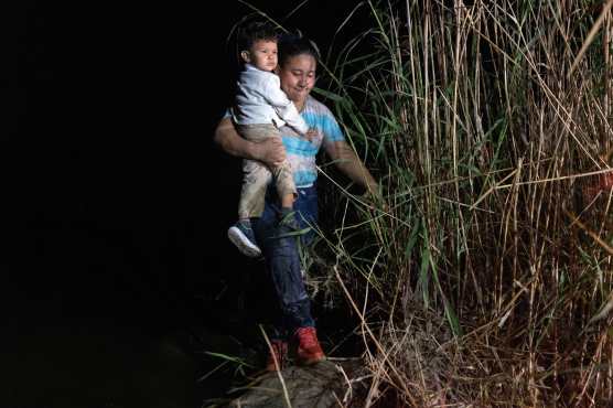 Una madre migrante pisa suelo estadounidense después de ser contrabandeada con su hijo a través de la frontera entre Estados Unidos y México en Roma, Texas. (Foto Prensa Libre: AFP)