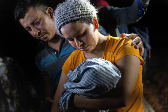 Los padres migrantes sostienen a su bebé después de que fueron contrabandeados a través de la frontera entre Estados Unidos y México en Roma, Texas. (Foto Prensa Libre: AFP)