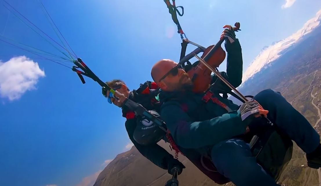 Hombre vuela en parapente y toca violín. (Foto Prensa Libre: Tomada de YouTube/CatersClips)