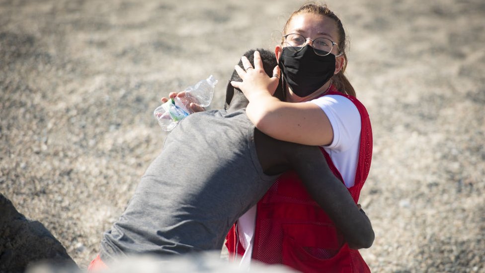 En esta foto, del 18 de mayo, capturada por Marcos Moreno, se ve a Luna Reyes, voluntaria de la Cruz Roja, brindándole ayuda al inmigrante que acababa de salir del mar. (MARCOS MORENO/ANADOLU AGENCY VIA GETTY IMAGES)