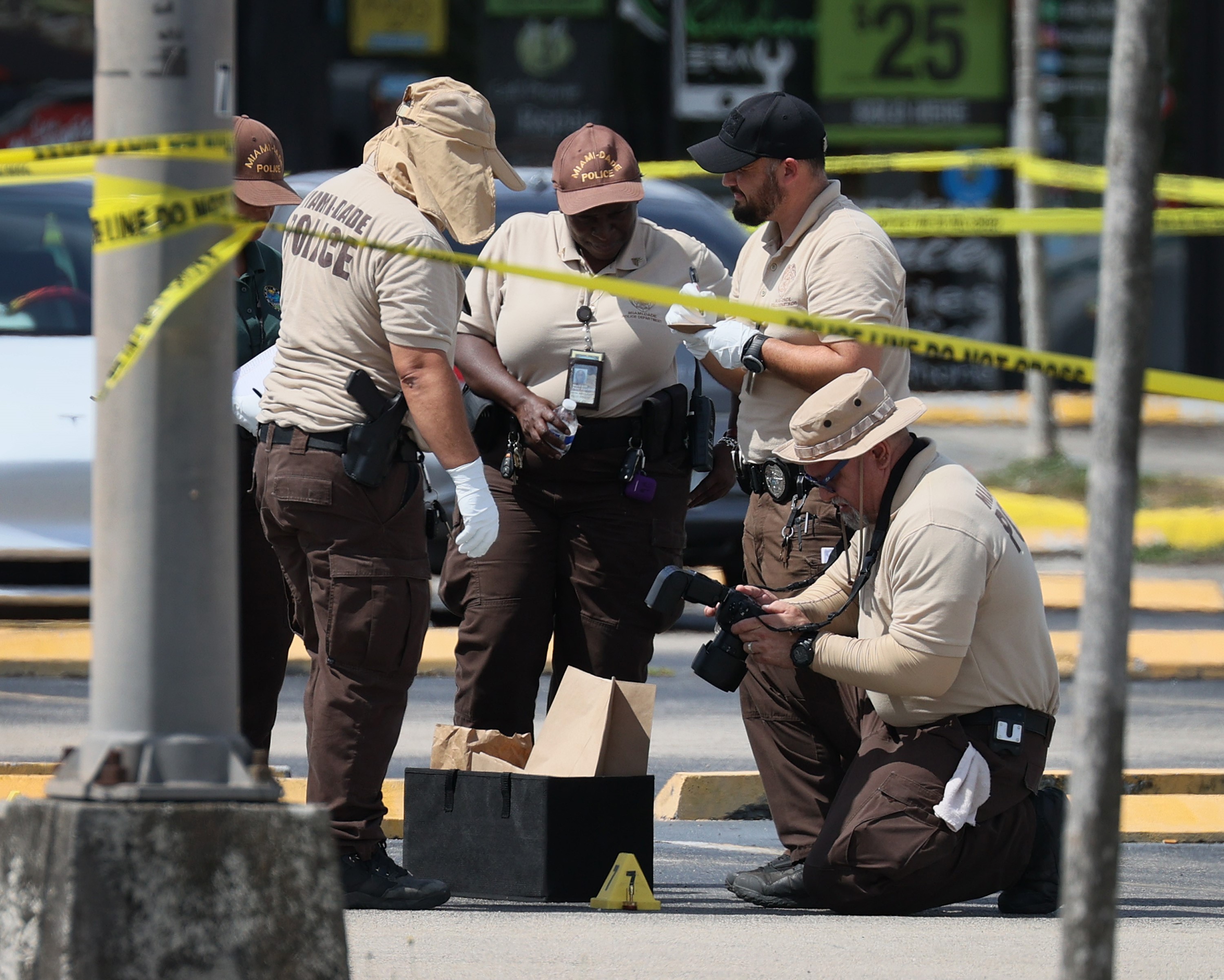 HIALEAH, FLORIDA - MAY 30: Miami-Dade police officers collect evidence near shell case evidence markers where a mass shooting took place outside of a banquet hall on May 30, 2021 in Hialeah, Florida. Police say that two people died, and an estimated 20 to 25 people are injured after the shooting at the banquet hall rented out for a concert. Joe Raedle/Getty Images/AFP == FOR NEWSPAPERS, INTERNET, TELCOS & TELEVISION USE ONLY ==