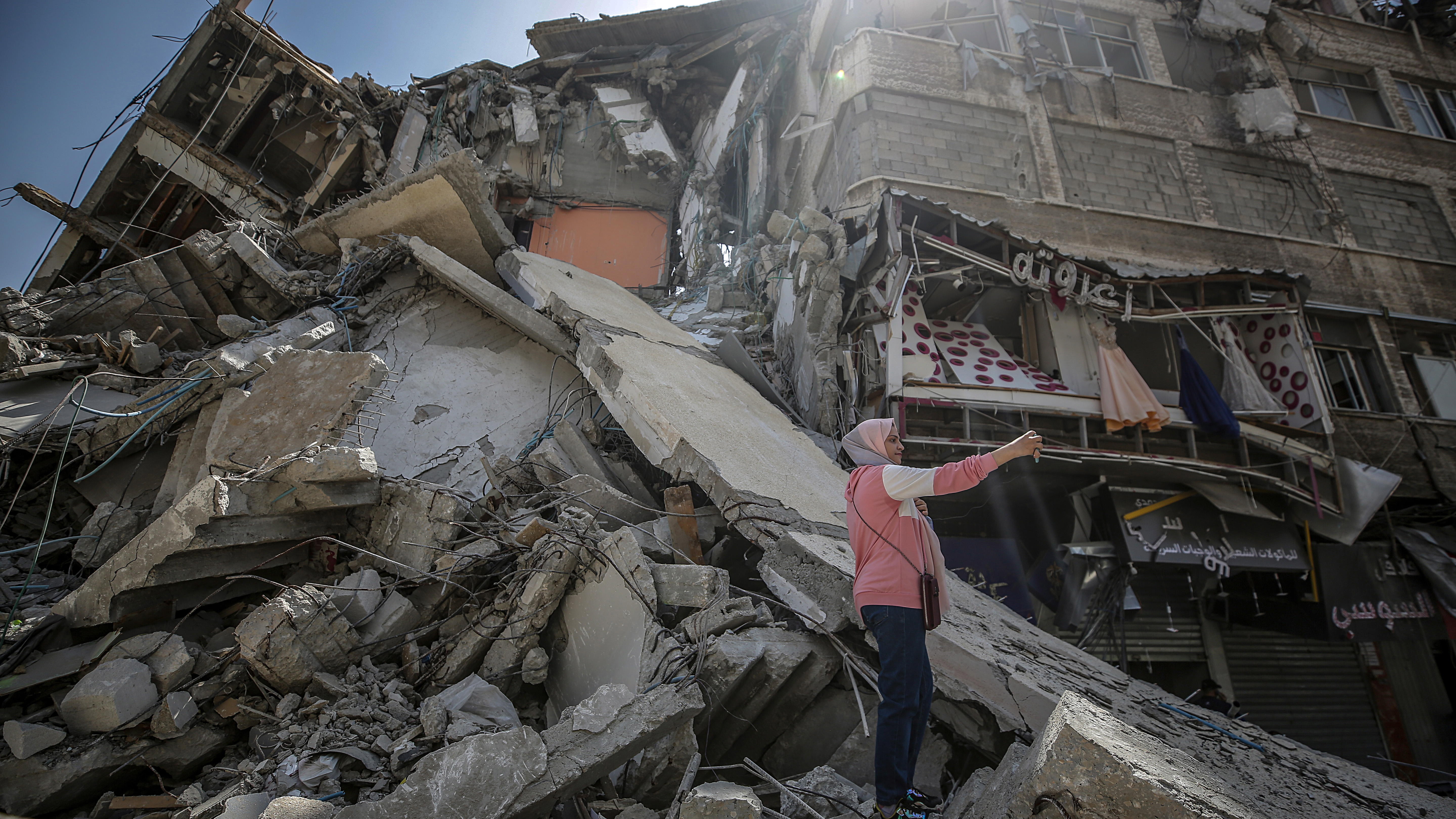 Beit Hanun (---), 21/05/2021.- A Palestinian girl takes selfie with her mobile in front of the rubble of the destroyed Al-Shorouq tower after a ceasefire between Israel and Gaza fighters, in Beit Hanun, northern Gaza Strip, 21 May 2021. After 11 days of fighting a ceasefire came into effect between Israel and militants in Gaza strip under an Egyptian initiative for an unconditional ceasefire. At least 232 Palestinians were killed in the Israeli offensive according to Palestinian health ministry, while at least 12 Israelis killed in rocket attacks from Gaza. (Atentado, Incendio, Egipto) EFE/EPA/MOHAMMED SABER