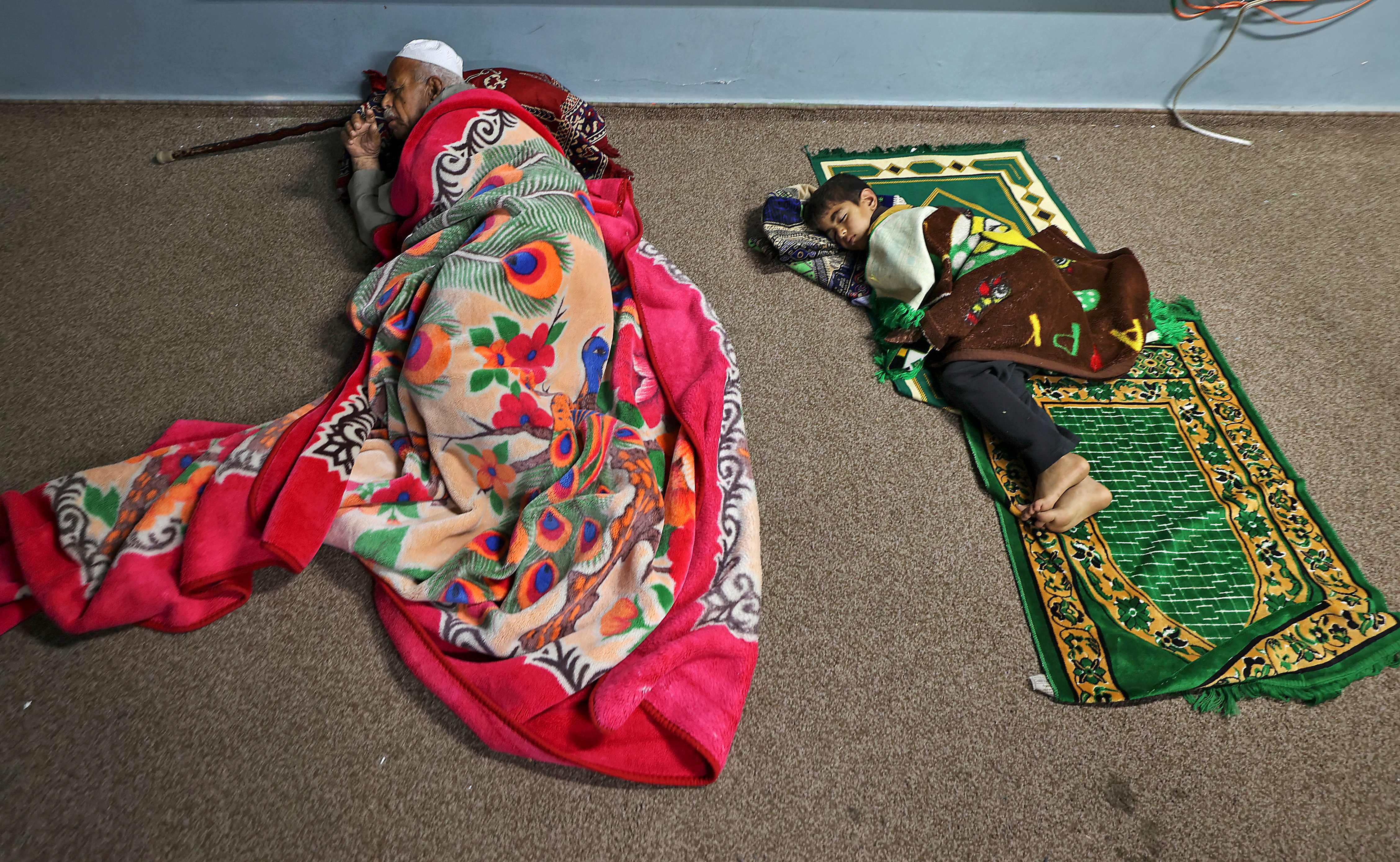 Palestinians sleep in a UN school in Gaza City on May 13, 2021, after fleeing from their homes in the town of Beit Lahia. - Israel pounded Gaza and deployed extra troops to the border Thursday as Palestinians fired barrages of rockets back, with the death toll in the enclave on the fourth day of conflict climbing to over 100. (Photo by MAHMUD HAMS / AFP)