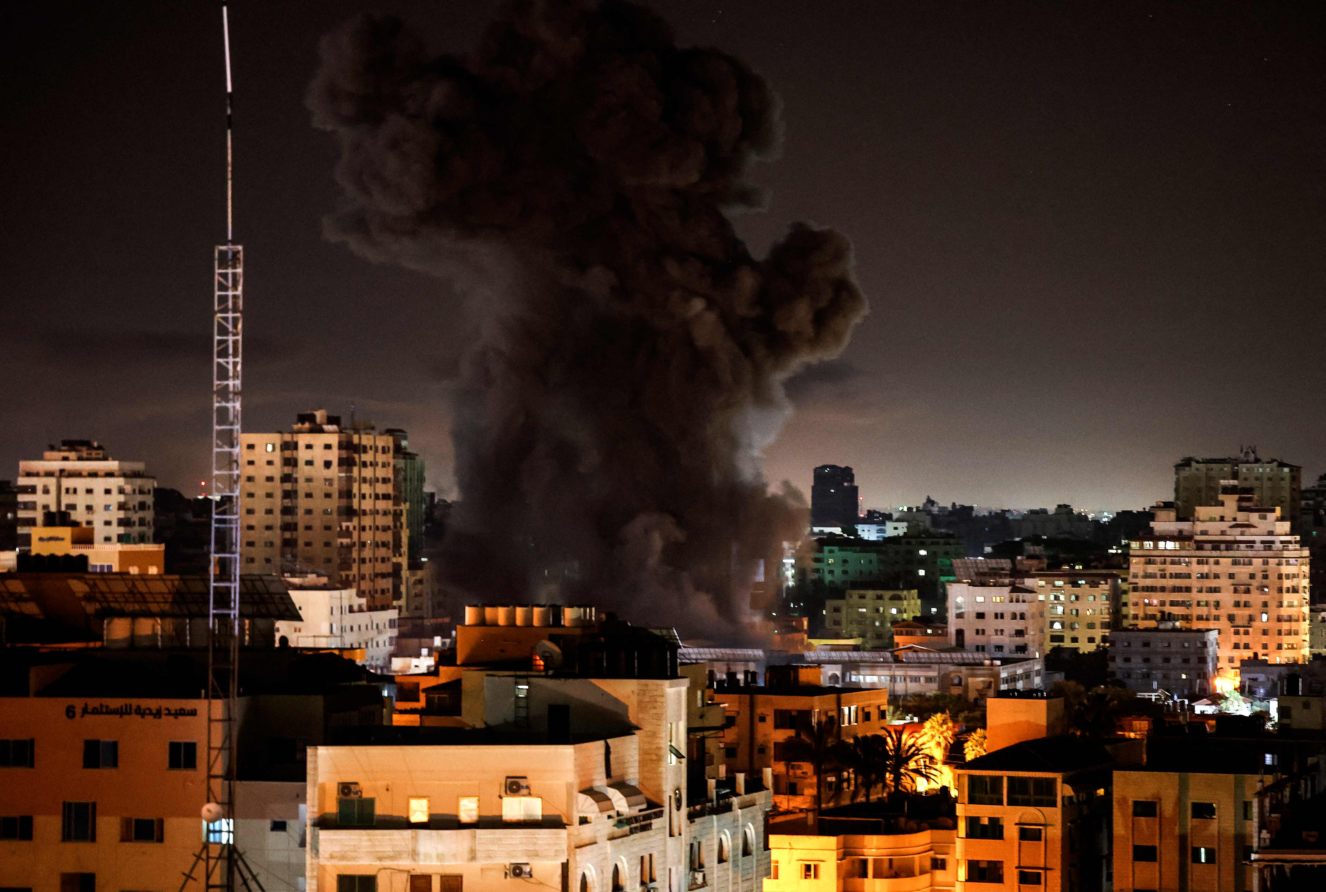 A plume of smoke rises above buildings in Gaza City as Israeli warplanes target the Palestinian enclave, early on May 17, 2021. (Photo by MAHMUD HAMS / AFP)