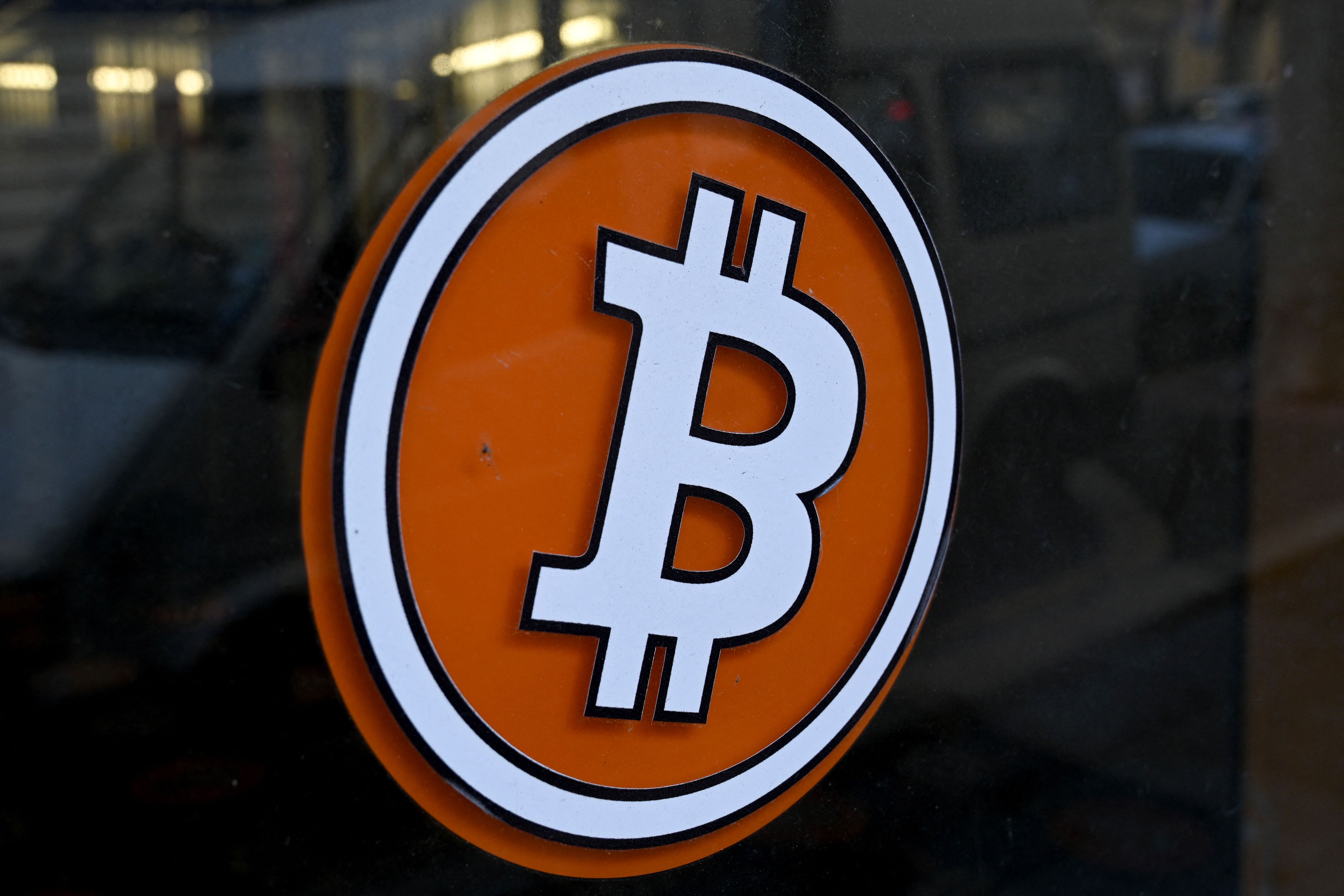 (FILES) This file photograph taken on January 8, 2021, shows a Bitcoin digital currency logo on the front door of an ATM in Marseille, southern France. - Bitcoin's value plunged on May 19, 2021, after China signaled a new crackdown on the cryptocurrency, but its losses were cushioned after Tesla head Elon Musk spoke up on Twitter. The virtual currency fell to almost $30,000 -- less than half the record value it reached last month -- before climbing back over $39,500 around 2000 GMT. It was still above its level at the start of the year. Bitcoin recovered somewhat following tweets from Musk that featured a diamond and hands emoji, taken as a signal the company had not sold off its huge bitcoin holdings as the CEO appeared to suggest recently. (Photo by NICOLAS TUCAT / AFP)