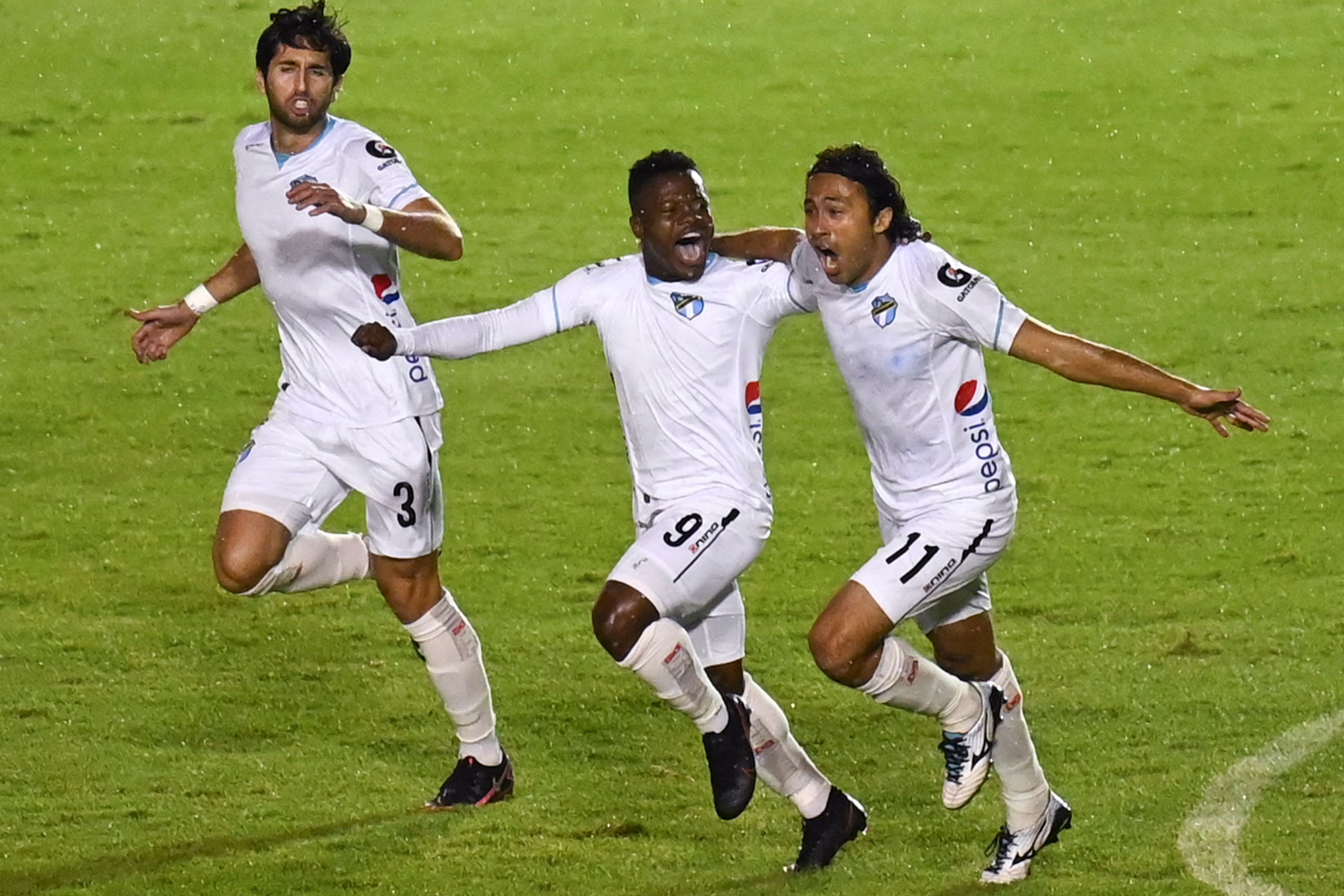 Comunicaciones's Junior Lacayo (C) celebrates with teammates Nicolas Samayoa (L) and Agustin Herrera after scoring against Santa Lucia during the 2021 Guatemalan Clausura Tournament final football match at Doroteo Guamuch Flores stadium in Guatemala City on May 23, 2021. (Photo by Johan ORDONEZ / AFP)