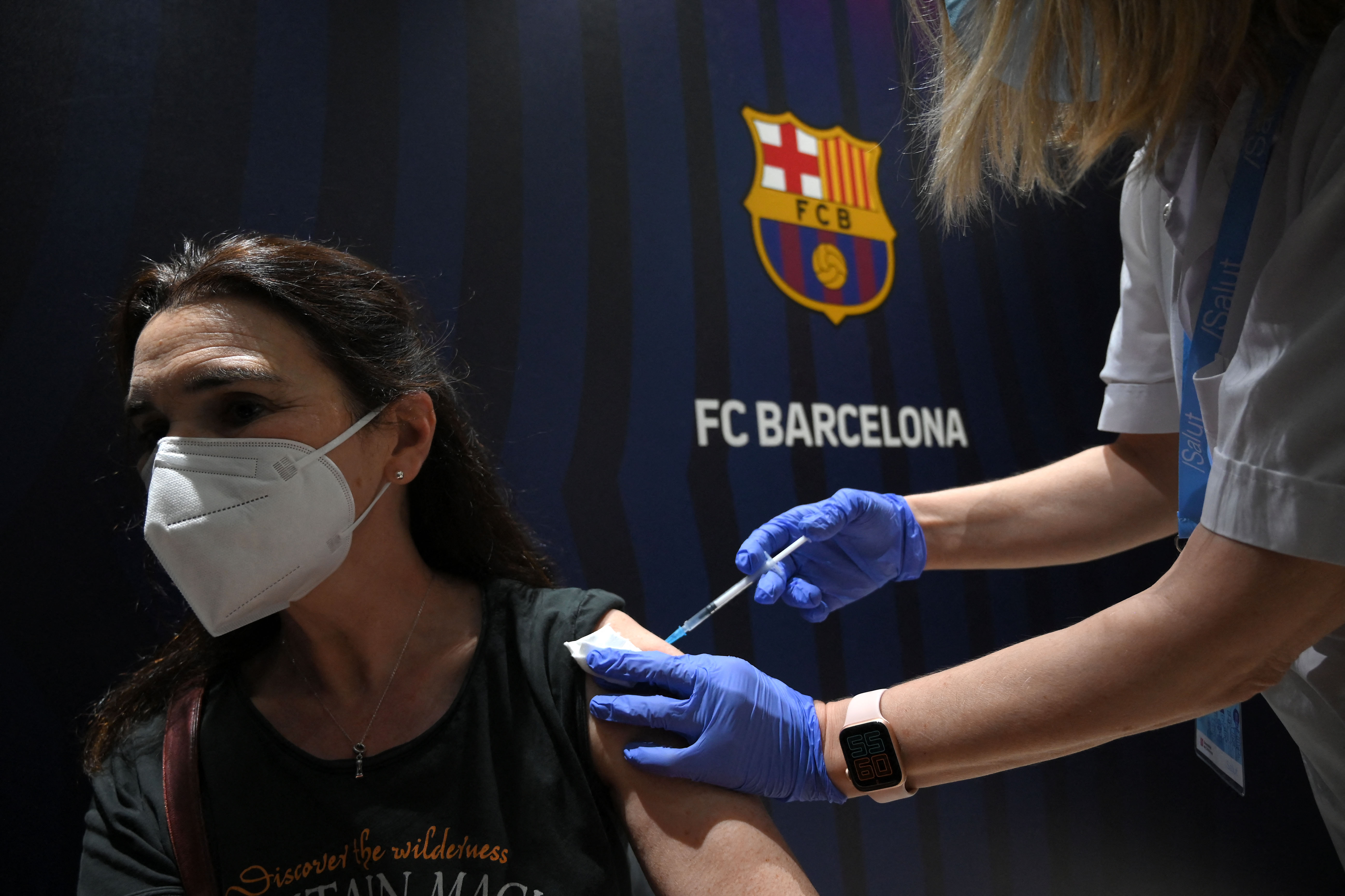 A woman receives a jab of the Pfizer-BioNTech vaccine during a vaccination campaign against COVID-19 at the Camp Nou stadium in Barcelona on May 27, 2021. (Photo by LLUIS GENE / AFP)