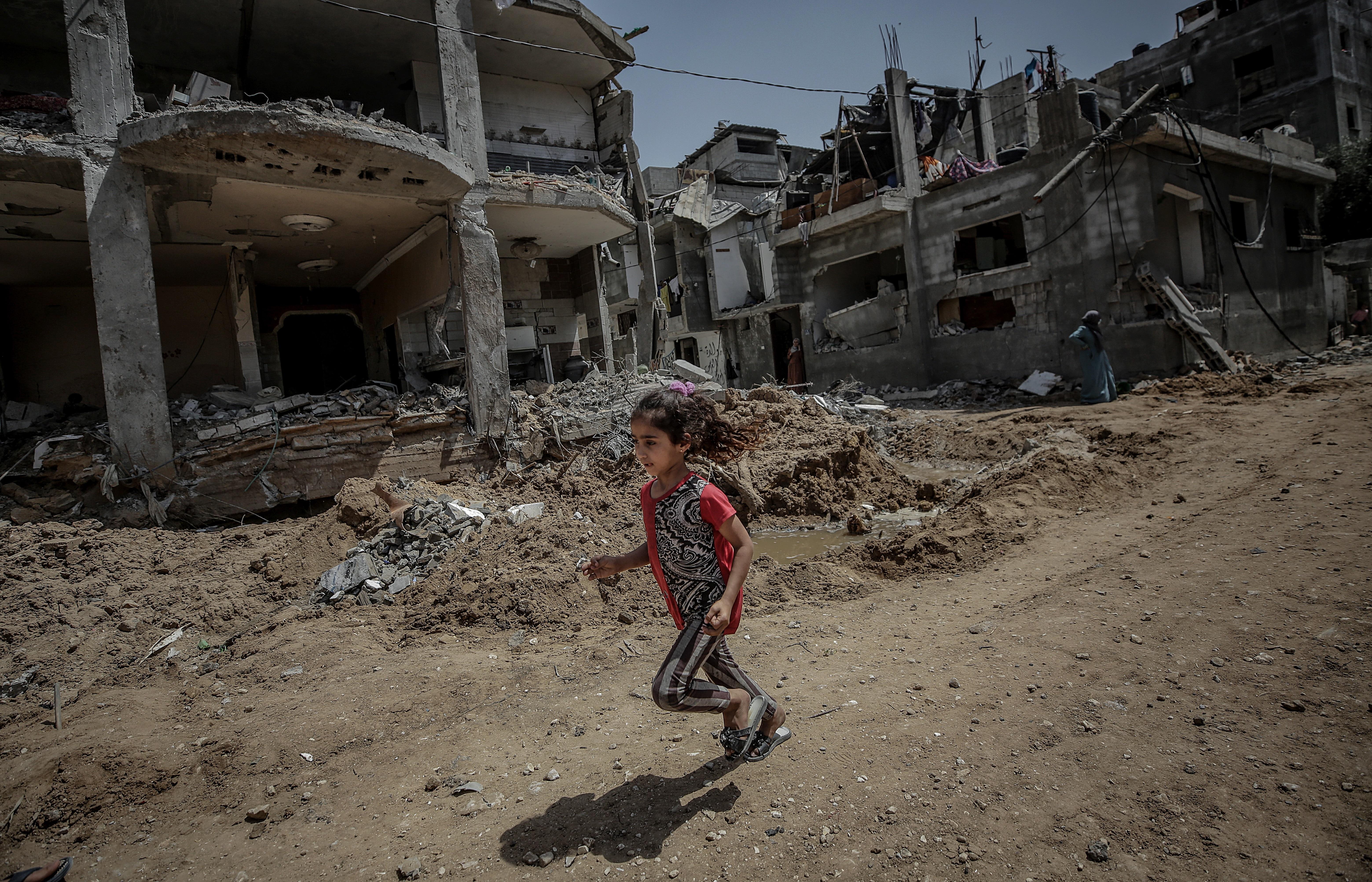Una niña palestina corre este viernes cerca de la destruida casa de su familia, en la Franja de Gaza. (Foto Prensa Libre: EFE)