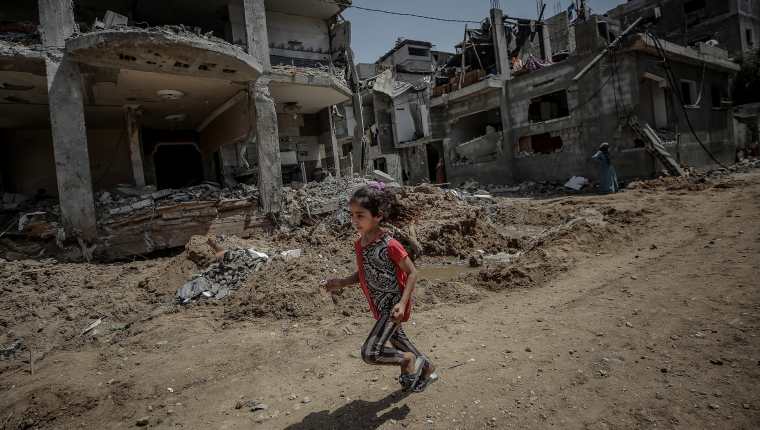 Una niña palestina corre este viernes cerca de la destruida casa de su familia, en la Franja de Gaza. (Foto Prensa Libre: EFE)
