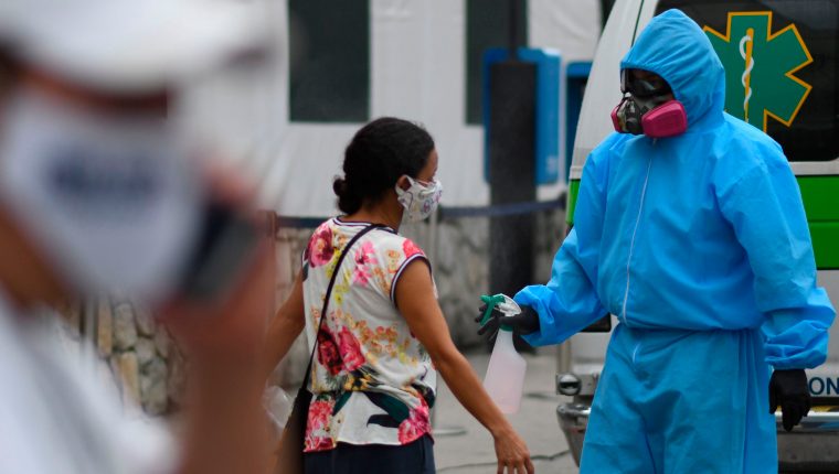 A medical staff sanitizes a woman outside  the Hospital General de Enfermedades (General Hospital for Diseases), in Guatemala City on July 13, 2020. - Doctors, deputies and the Human Rights Procurators Office (PDH) have raised the alarm about the imminent collapse of Guatemala's health system due to the increase of COVID-19 cases. (Photo by Johan ORDONEZ / AFP)