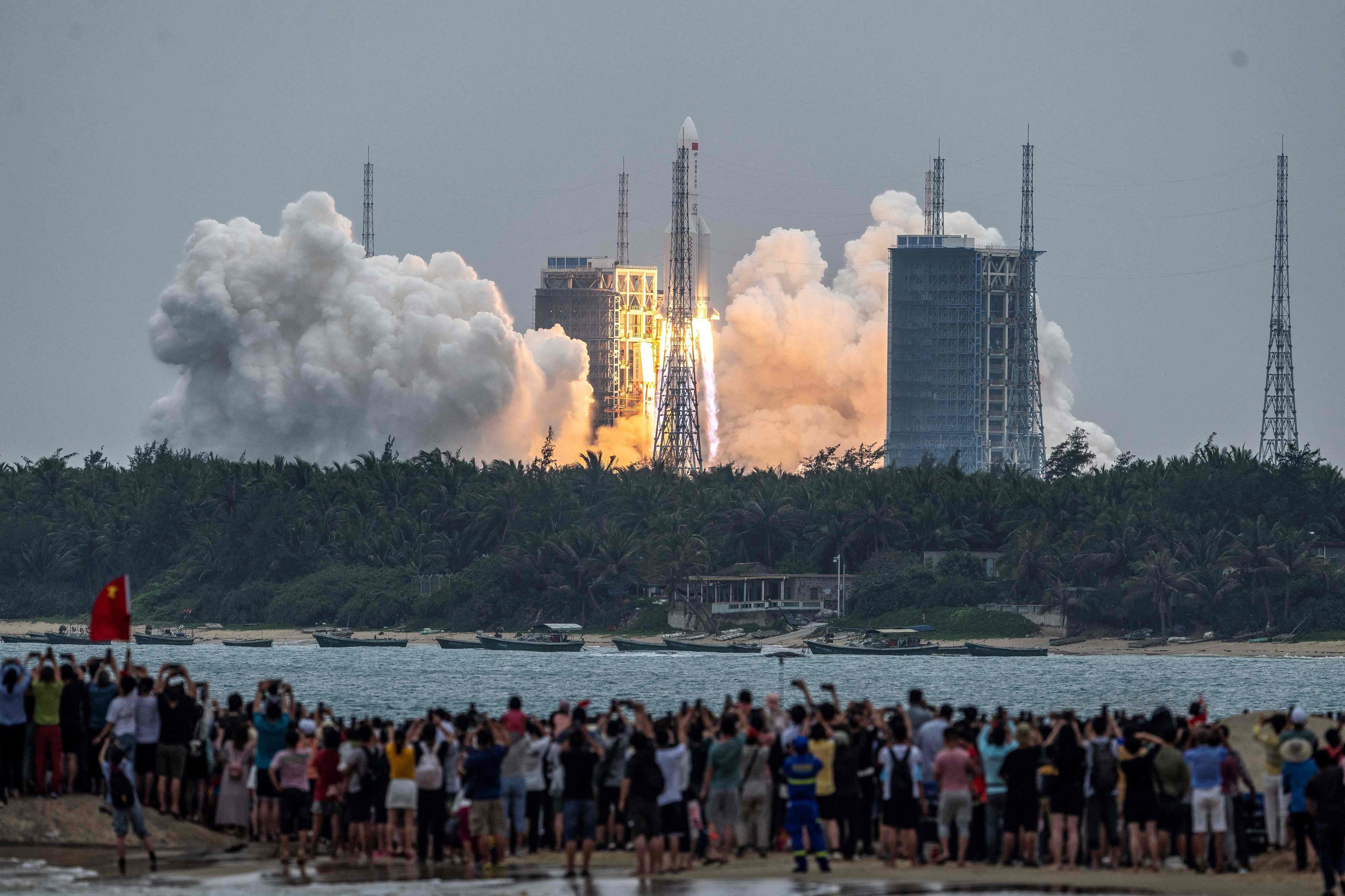 Varias personas observaron el cohete Long March 5B, mientras despegó del Centro de Lanzamiento Espacial Wenchang en la provincia de Hainan, en el sur de China, el 29 de abril de 2021. (Foto Prensa Libre: AFP) 