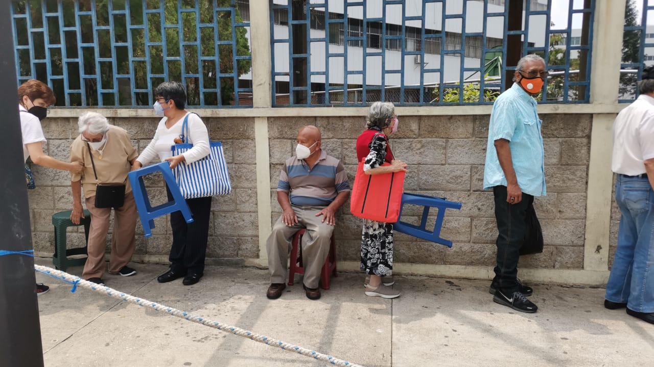 Muchos adultos mayores hicieron fila bajo el sol y debieron llevar bancos para descansar mientras esperaban para recibiré la primera dosis de la vacuna. (Foto Prensa Libre: María José Bonilla) 	