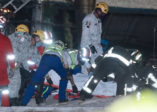 Miembros de los servicios de emergencia rescatan un cuerpo tras el colapso de los vagones del metro en la Ciudad de México. (Foto Prensa Libre: EFE)