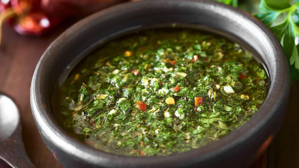 El chimichurri es una mezcla de perejil finamente picado, orégano, chile molido y ajo mezclado con vinagre y aceite vegetal.