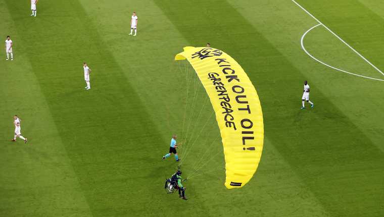 Un activista de la organización  Greenpeace se lanzó en un paracaídas antes de que diera inicio el juego de Francia vs. Alemania. Foto Prensa Libre: EFE.