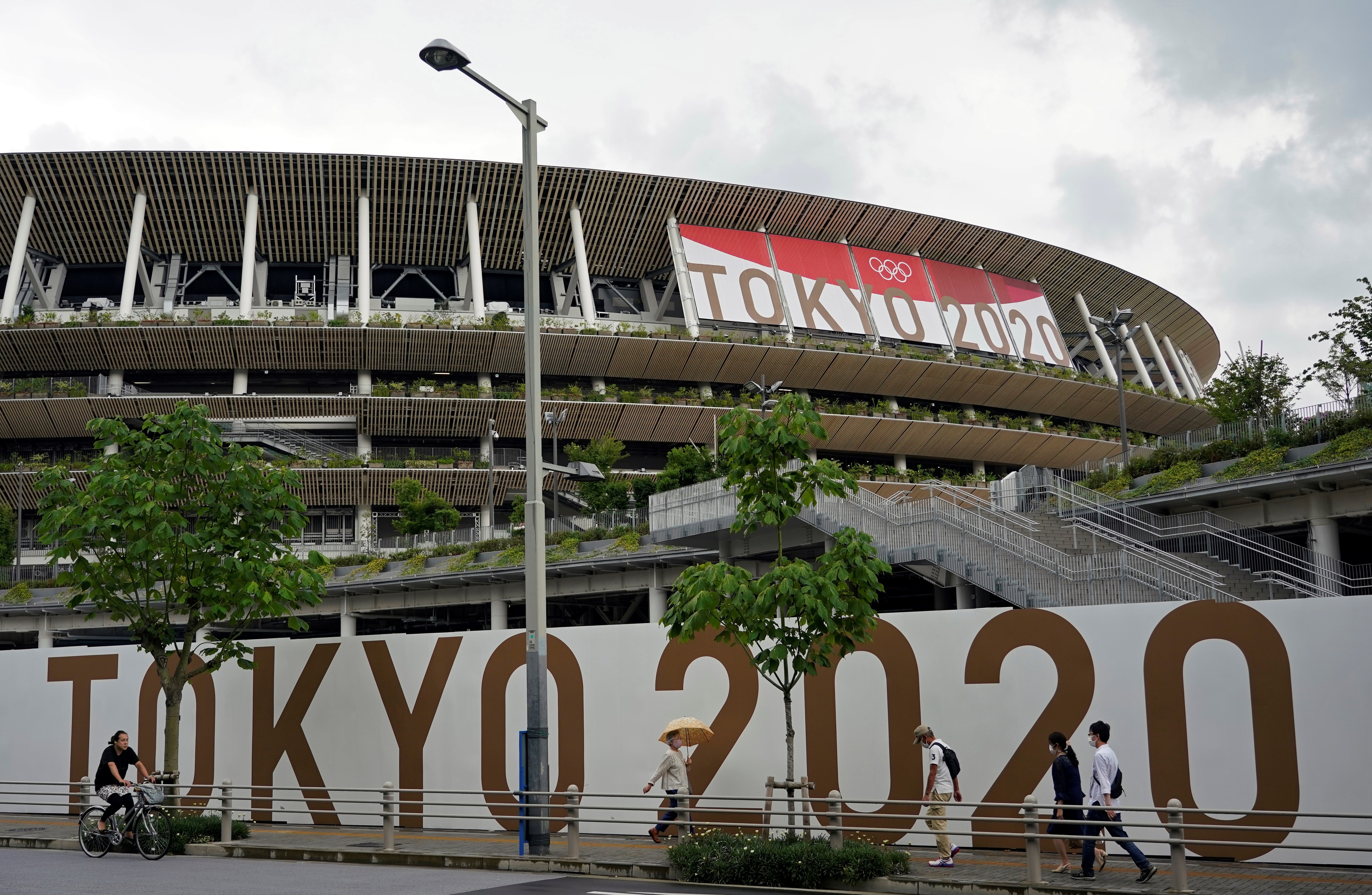 Tokyo (Japan), 23/06/2021.- Passersby walk past the National Stadium, the main stadium of the 2020 Tokyo Olympic Games, in Tokyo, Japan, 23 June 2021, one month before the opening of the Tokyo 2020 Olympic Games. The National Stadium will host the opening, closing ceremonies and the athletics events. The Summer Games were postponed due to COVID-19 Coronavirus pandemic. (Abierto, Japón, Tokio) EFE/EPA/FRANCK ROBICHON