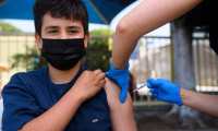 Simon Huizar, 13, receives a first dose of the Pfizer Covid-19 vaccine at a mobile vaccination clinic at the Weingart East Los Angeles YMCA on May 14, 2021 in Los Angeles, California. - The campaign to immunize America's 17 million adolescents aged 12-to-15 kicked off in full force on May 13. The YMCA of Metropolitan Los Angeles is working to overcome vaccine hesitancy and expand access in high risk communities with community vaccine clinics in the area. (Photo by Patrick T. FALLON / AFP)
