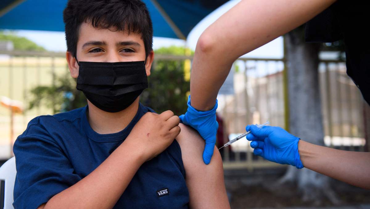 Simon Huizar, 13, receives a first dose of the Pfizer Covid-19 vaccine at a mobile vaccination clinic at the Weingart East Los Angeles YMCA on May 14, 2021 in Los Angeles, California. - The campaign to immunize America's 17 million adolescents aged 12-to-15 kicked off in full force on May 13. The YMCA of Metropolitan Los Angeles is working to overcome vaccine hesitancy and expand access in high risk communities with community vaccine clinics in the area. (Photo by Patrick T. FALLON / AFP)