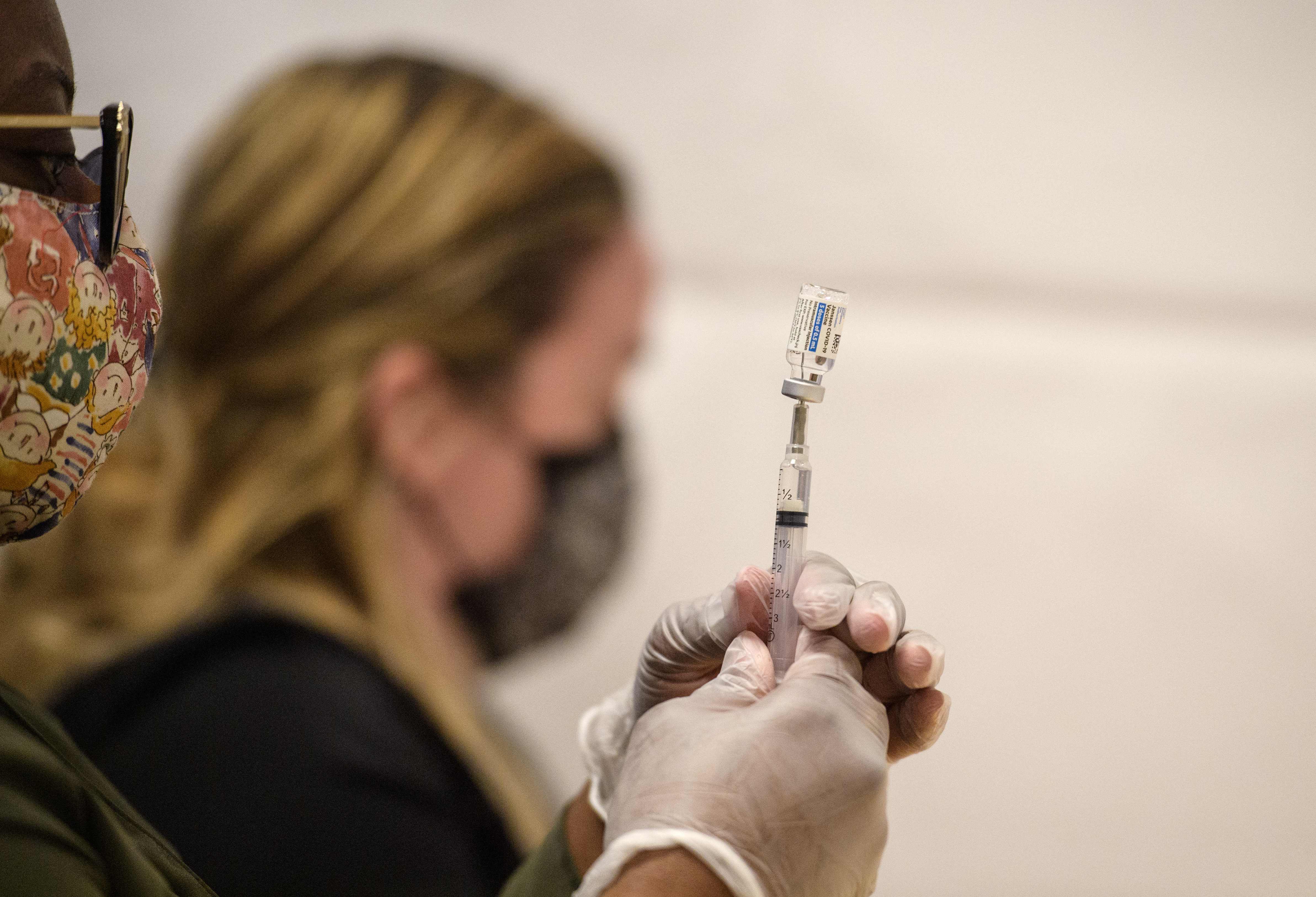 (FILES) In this file photo healthcare workers prepare a syringe with a vial of the J&J/Janssen Covid-19 vaccine at a temporary vaccination site at Grand Central Terminal train station on May 12, 202 in New York City. - Goldman Sachs has ordered US employees to report their vaccination status as the investment bank orchestrates a return to the office, according to a staff memo reviewed on June 10, 2021 by AFP. 