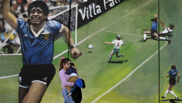 En esta foto, tomada el 30 de octubre de 2020, una mujer pasa por un mural del artista "Uasen" que riden tributo al gol del siglo de Diego Maradona. Foto Prensa Libre: AFP.