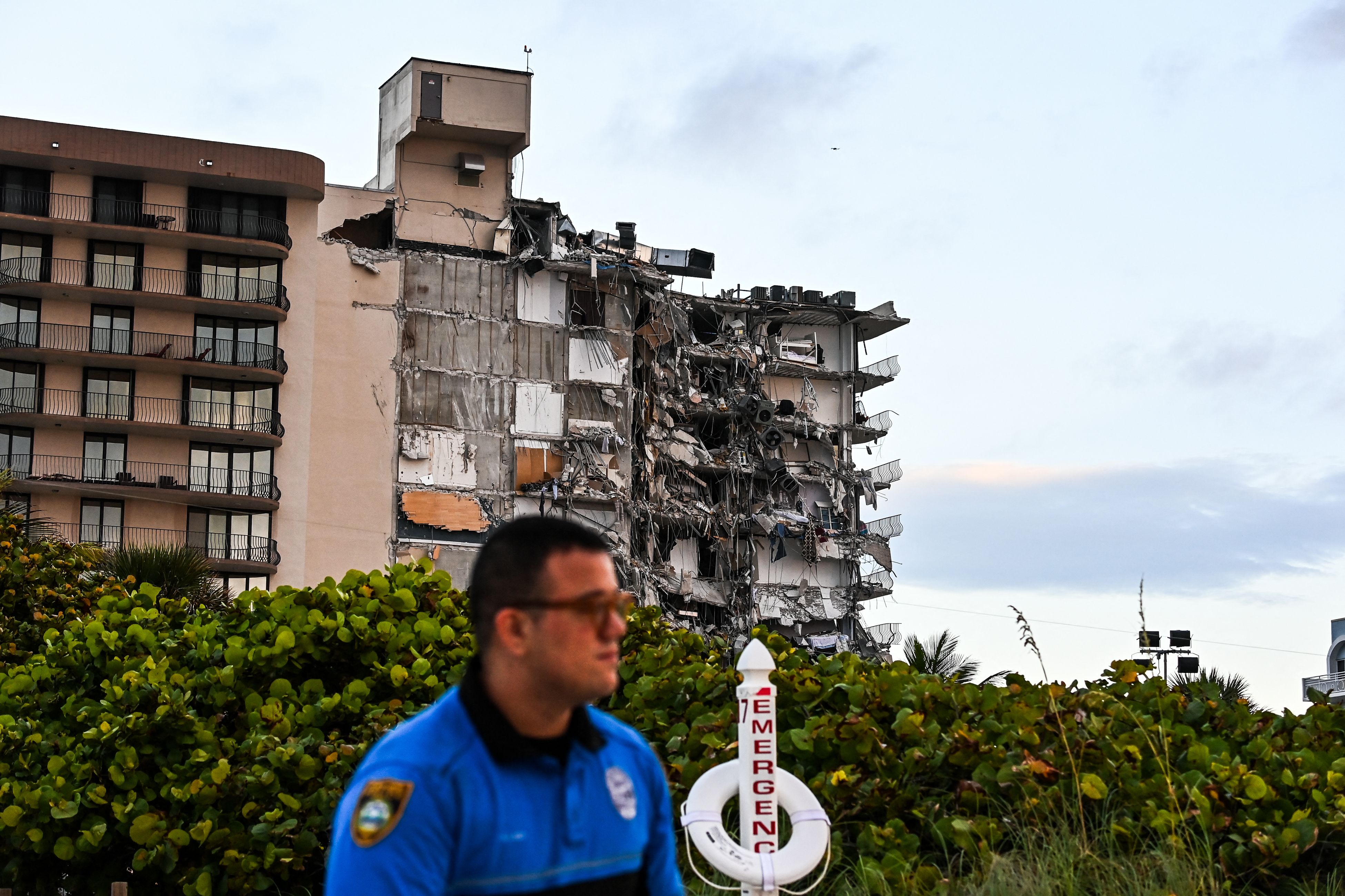 Un oficial de policía de Miami Beach resguarda un área cercana al edificio que se derrumbó en Surfside, en el norte de Miami Beach. (Foto Prensa Libre: AFP)