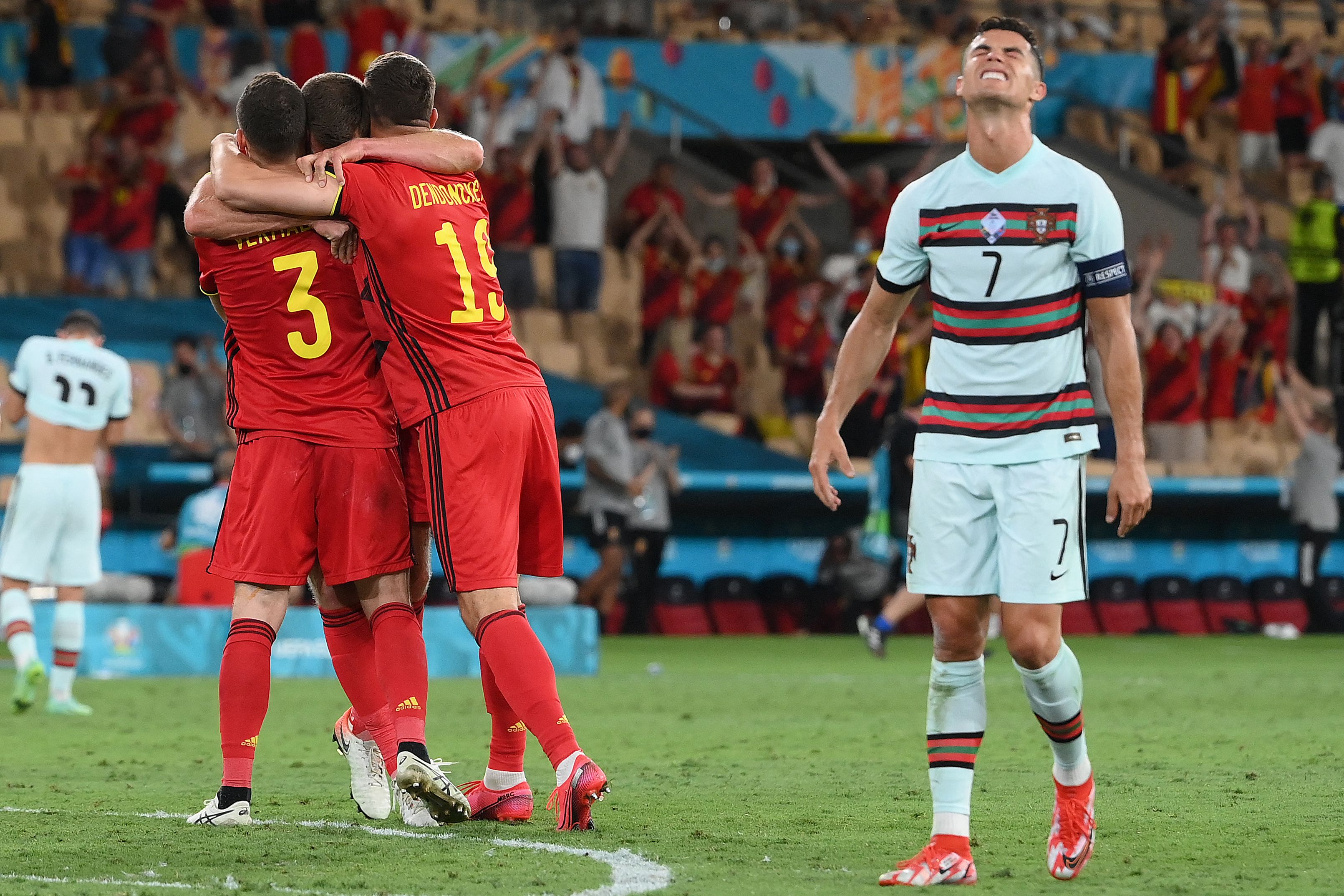 Portugal's forward Cristiano Ronaldo (R) reacts as Belgium's players celebrate their victory at the end of the UEFA EURO 2020 round of 16 football match between Belgium and Portugal at La Cartuja Stadium in Seville on June 27, 2021. (Photo by LLUIS GENE / POOL / AFP)