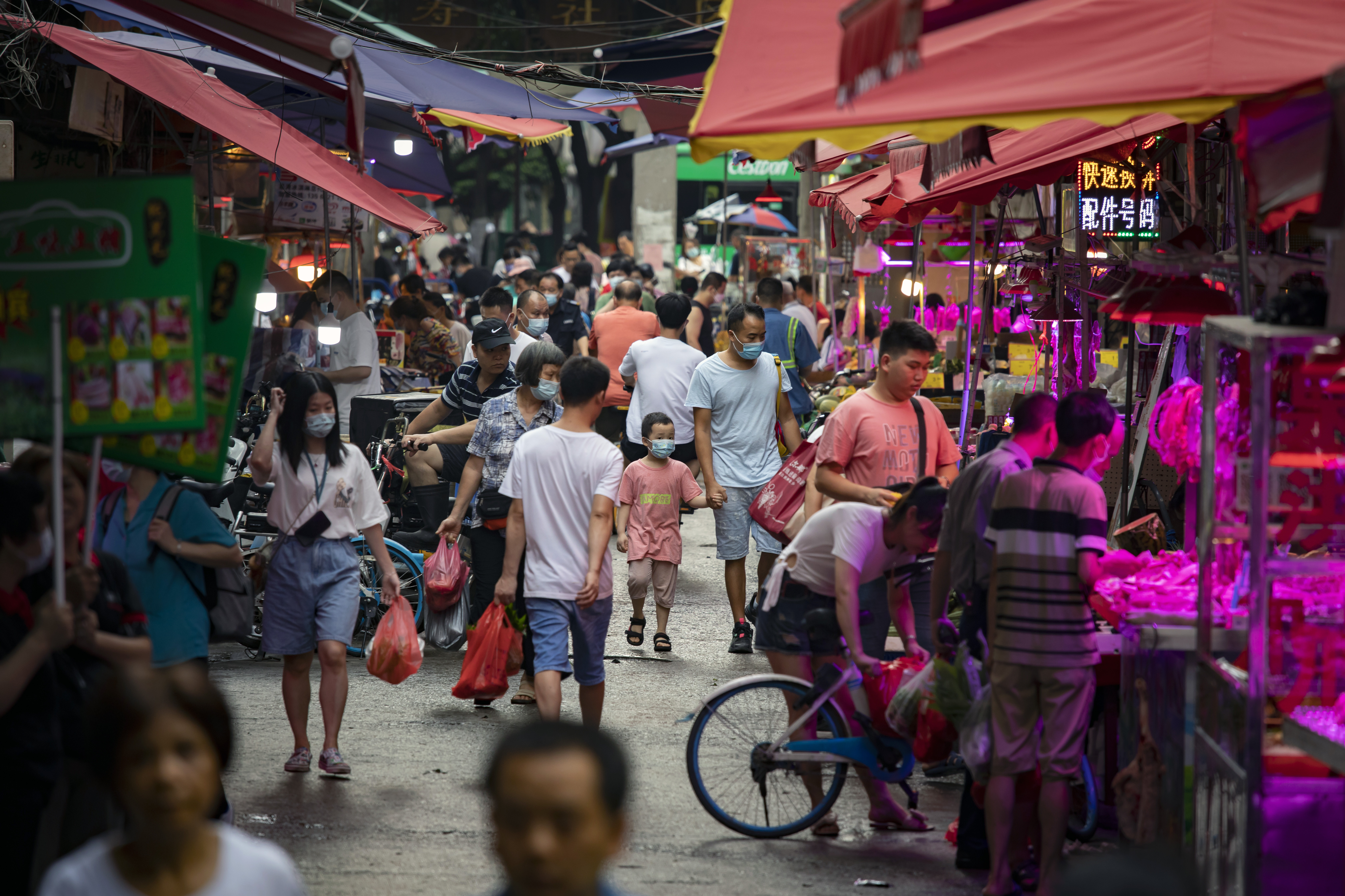 Hombre lleva a un niño de la mano en un mercado de Guangzhou, China, el 24 de mayo de 2021.   (Foto Prensa Libre: Qilai Shen/The New York Times)