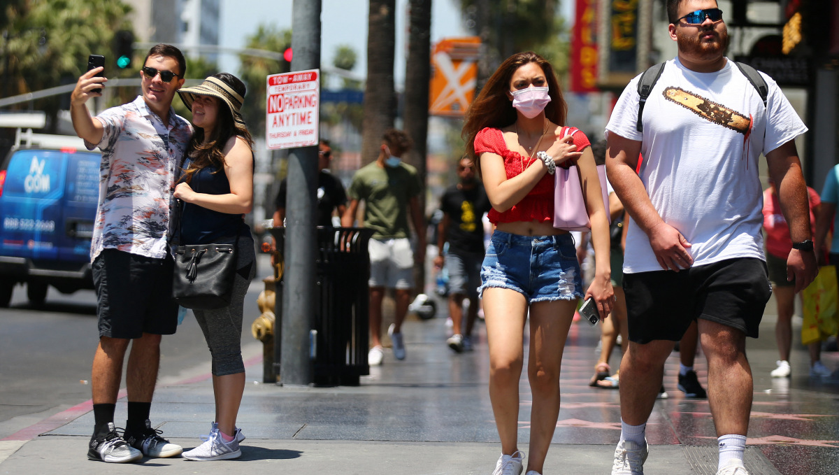 LOS ANGELES, CALIFORNIA - JUNE 15: People walk and take photos on Hollywood Boulevard on June 15, 2021 in Los Angeles, California. California, the first state in the U.S. to go into lockdown at the beginning of the coronavirus pandemic, is lifting nearly all COVID-19 restrictions today with the exceptions of mask wearing and social distancing on public transportation, hospitals, K-12 schools indoors and some retail stores. Mario Tama/Getty Images/AFP (Photo by MARIO TAMA / GETTY IMAGES NORTH AMERICA / Getty Images via AFP)