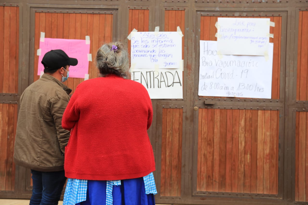 Vecinos de San José Pinula leen los carteles en la puerta del centro de vacunación. (Foto Prensa Libre: Byron García)