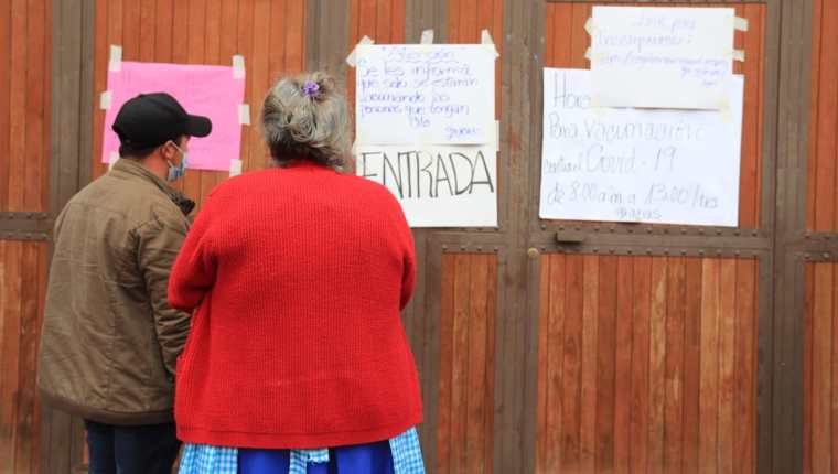 Vecinos de San José Pinula leen los carteles en la puerta del centro de vacunación. (Foto Prensa Libre: Byron García)