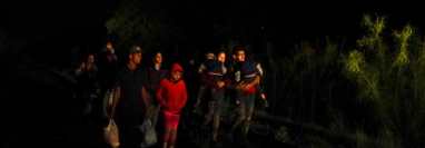 Un grupo de personas con hijos en sus brazos llega a un centro de procesamiento de migrantes que quieren asilarse en EE.UU., el 12 de mayo del 2021 en La Joya, Texas. (Foto Prensa Libre: Voz de América)
