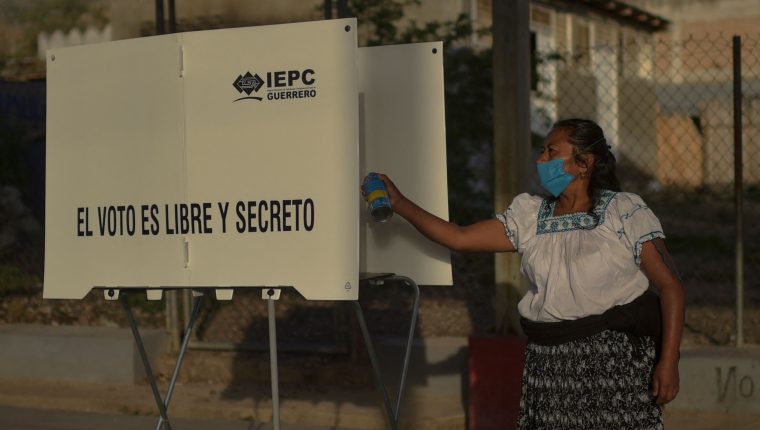 A member of a polling station disinfects the voting booth at a polling station in Nahuat community of Atzacoaloya, Guerrero state, Mexico, on June 6, 2021. - Mexicans began voting Sunday in elections seen as pivotal to President Andres Manuel Lopez Obrador's promised "transformation" of a country shaken by the coronavirus pandemic, a deep recession and drug-related violence. (Photo by PEDRO PARDO / AFP)