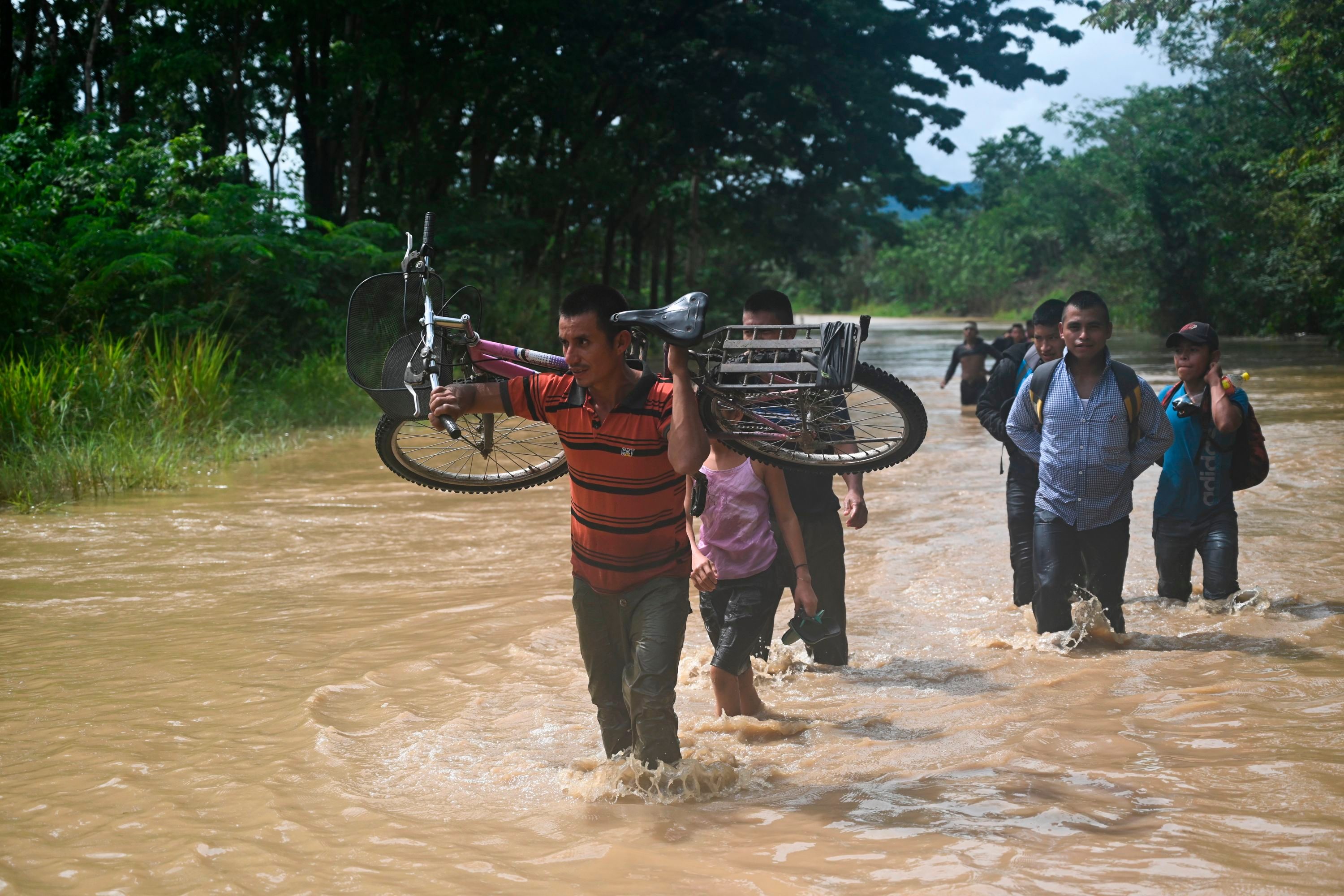 People wade through the water in a flooded area in Panzos, Alta Verapaz, 220 km north of Guatemala City on November 6, 2020 after the passage of Hurricane Eta -now degraded to a tropical storm. - About 150 people have either died or remain unaccounted for in Guatemala due to mudslides caused by powerful storm Eta, which buried an entire village, President Alejandro Giammattei said Friday. (Photo by Johan ORDONEZ / AFP)
