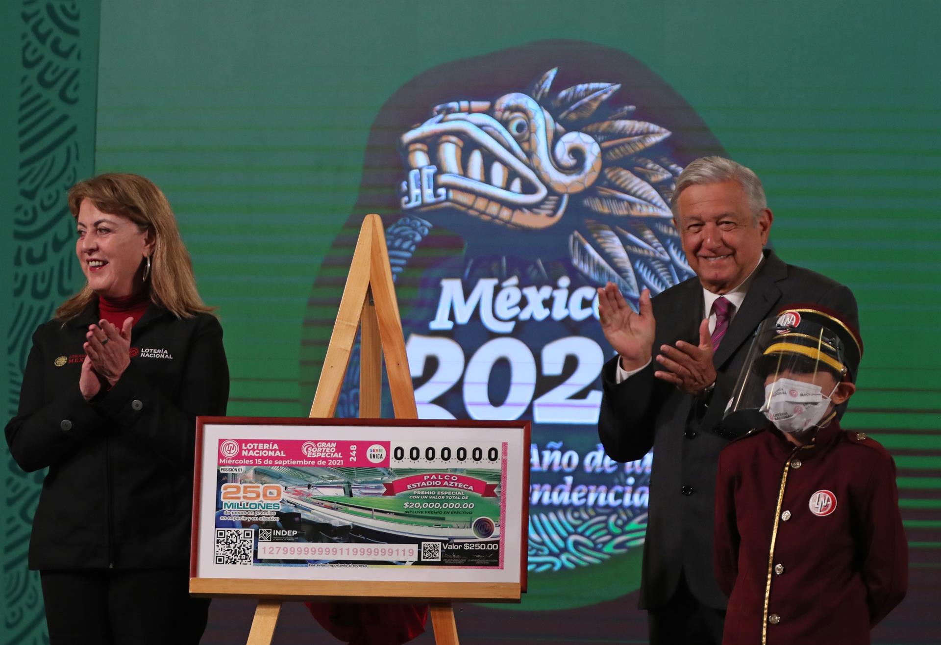 El presidente de México, Andrés Manuel López Obrador, acompañado de la directora general de la Lotería Nacional, Margarita González Saravia, develan un boleto para el sorteo del 15 de septiembre  de 2021. (Foto Prensa Libre: EFE)