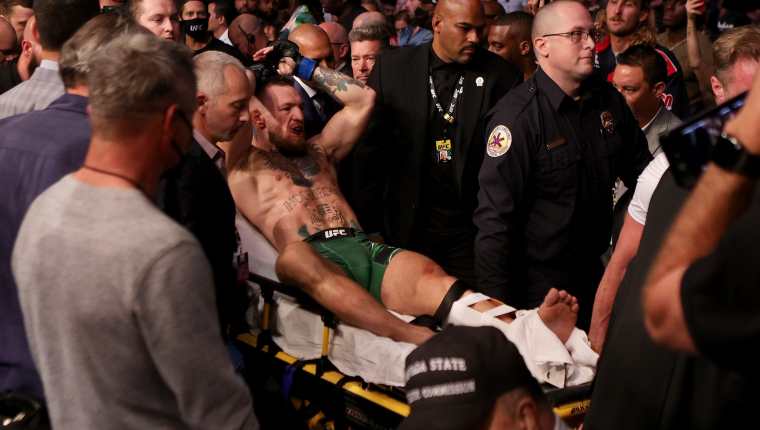 El irlandés Conor McGregor sale en una camilla después de haber peleado ante Dustin Poirier en el T-Mobile Arena. El luchador sufrió una fractura de tibia y peroné. Foto Prensa Libre: AFP. 