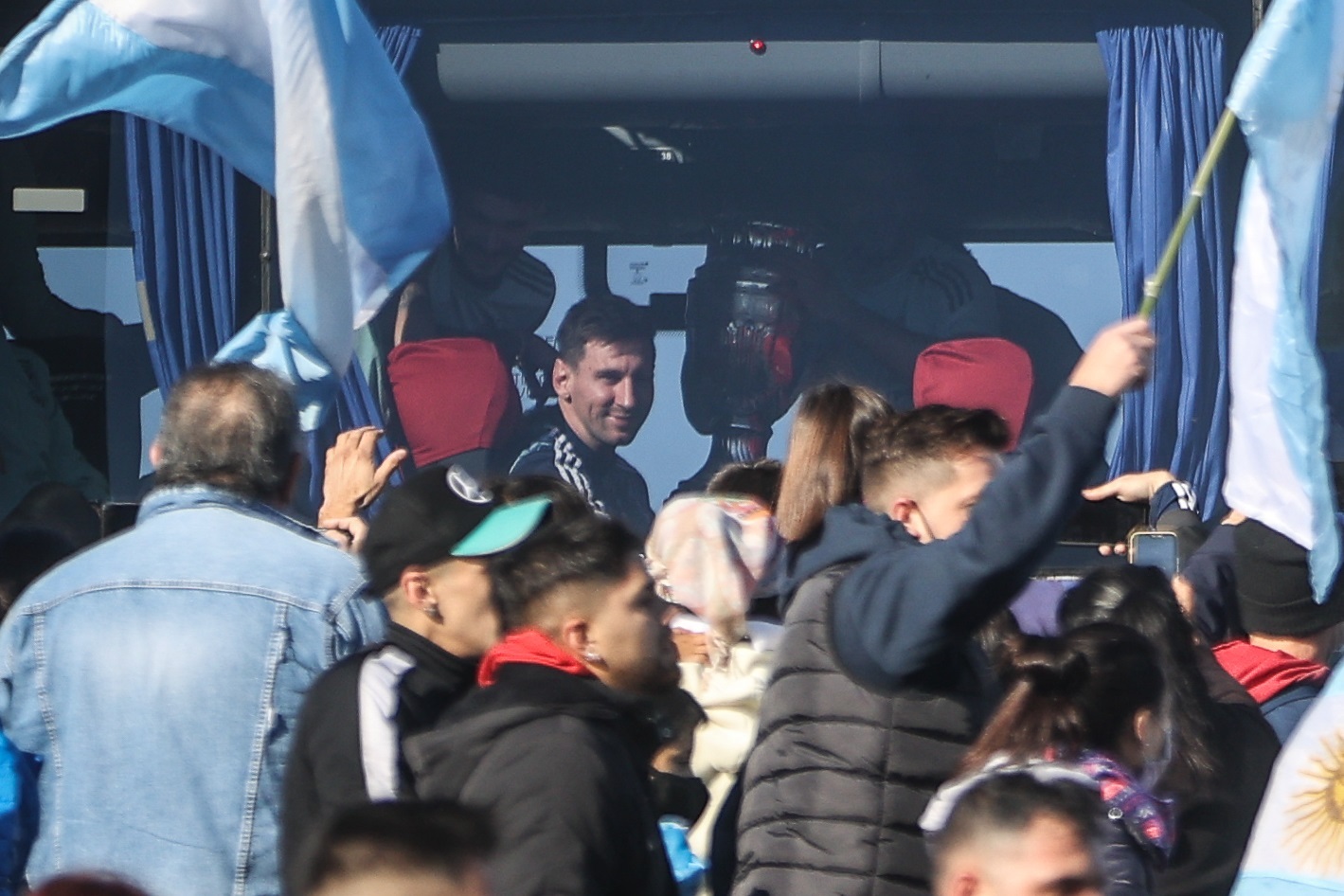 AME1621. BUENOS AIRES (ARGENTINA), 11/07/2021.- El jugador de la selección argentina Lionel Messi sonríe a los aficionados que le saludan fuera del autobús que transporta al equipo, luego de su arribo hoy a Buenos Aires (Argentina). Cientos de personas recibieron este domingo a la selección argentina campeona de la Copa América 2021. Argentina se impuso ayer por 1-0 a Brasil en la final de la Copa América con gol de Ángel Di María en el estadio Maracaná de Río de Janeiro y, con su decimoquinto trofeo continental, puso fin a un ayuno de 28 años sin títulos. EFE/ Juan Ignacio Roncoroni