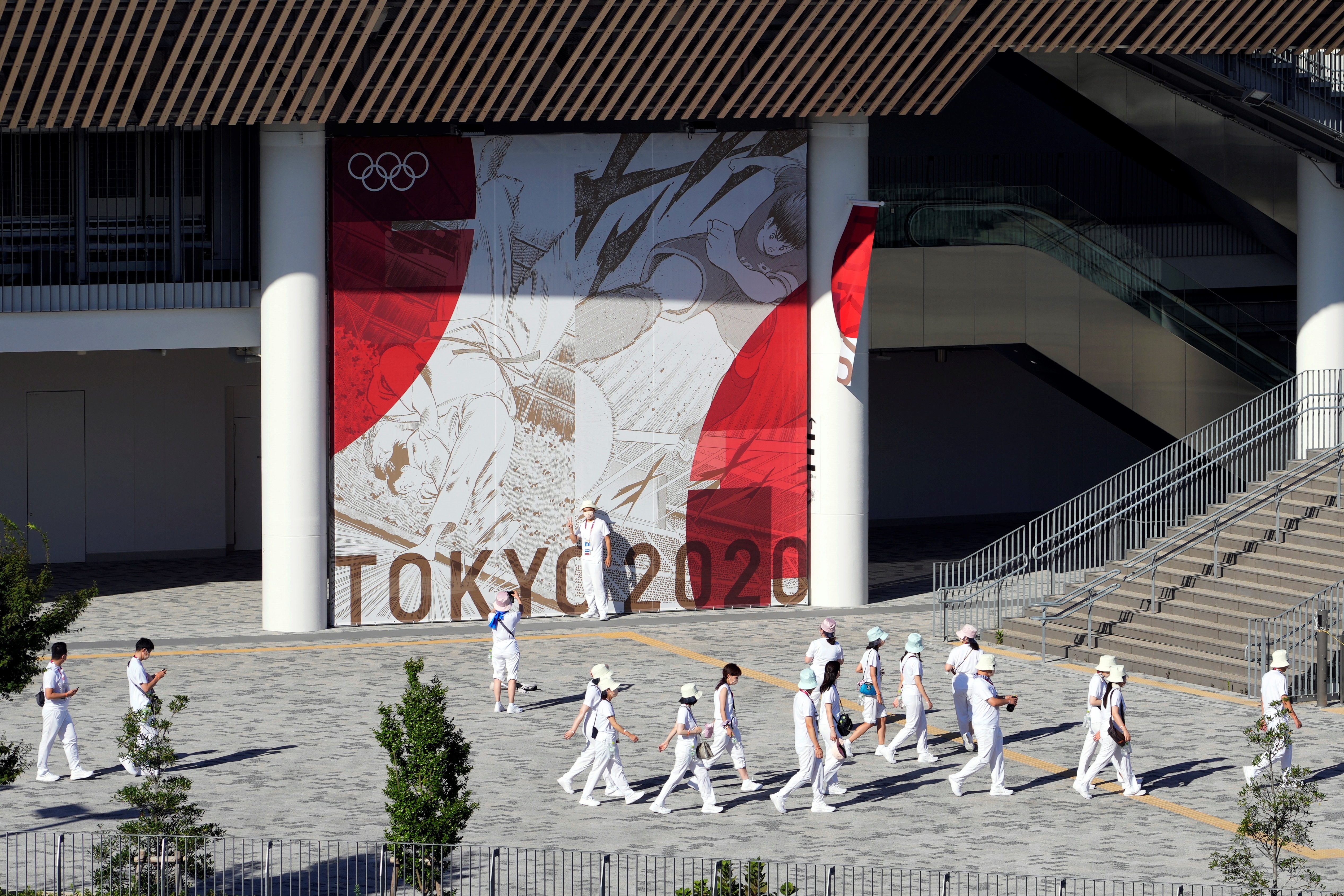 Tokyo (Japan), 18/07/2021.- Staff members walk next to the National Stadium in Tokyo, Japan, 18 July 2021. Just five days before the opening of the Tokyo Games, latest polls show that more than 85 per cent of the population are concerned about the Olympics as Tokyo recorded 1,000 new COVID-19 cases for the fifth straight day. (Abierto, Japón, Tokio) EFE/EPA/FRANCK ROBICHON