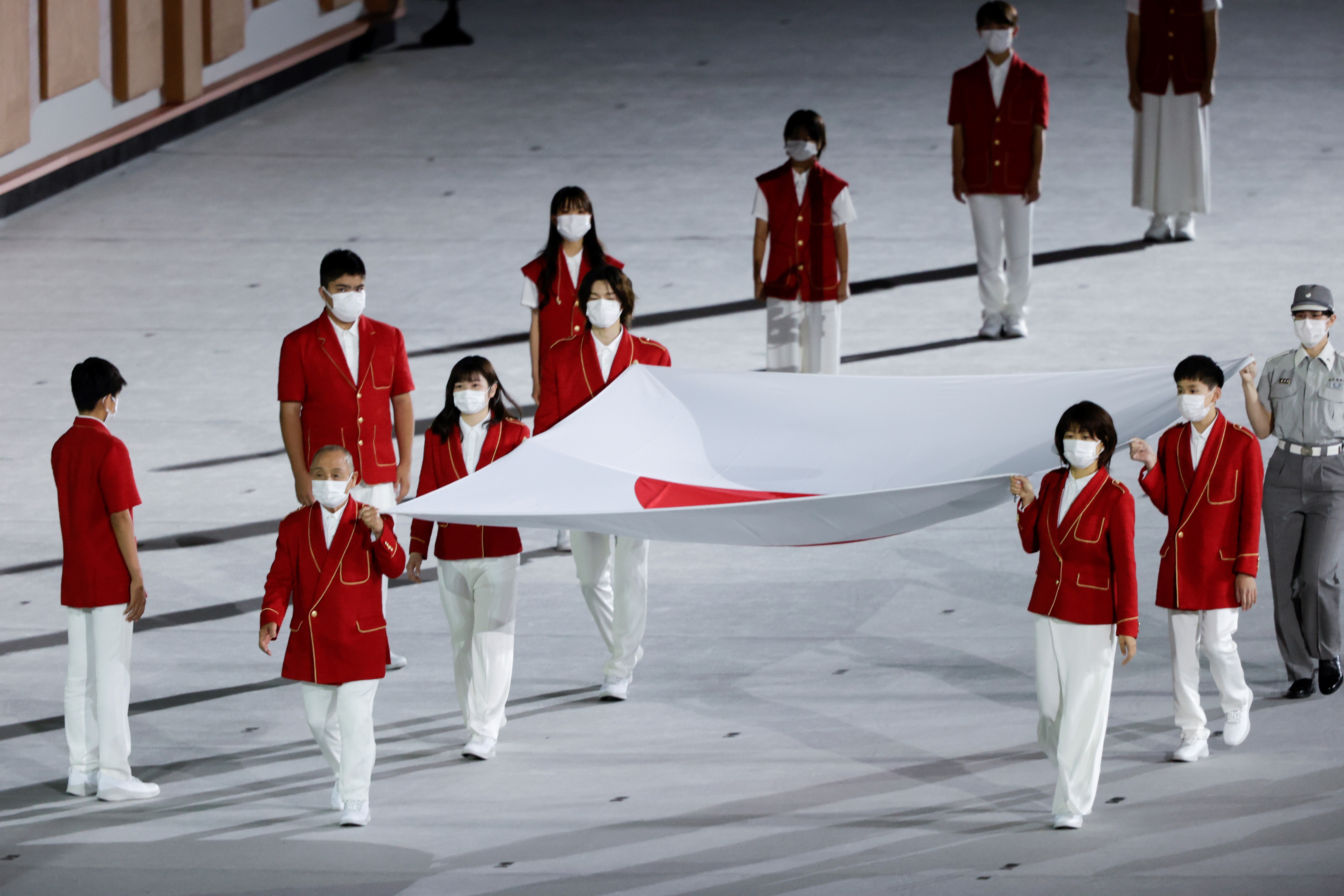 Deportistas nipones portan una bandera de Japón durante la ceremonia inaugural de los Juegos Olímpicos de Tokio 2020, este viernes en el Estadio Olímpico, que no contará con la presencia de público en las gradas. Foto Prensa Libre: EFE.