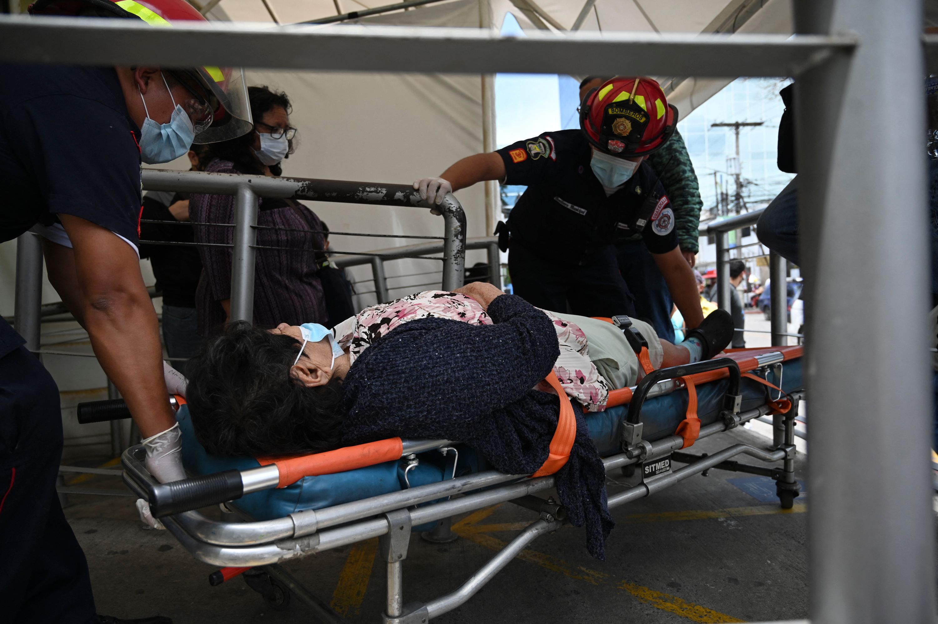 Municipal firefighters move a woman with symptoms of the novel coronavirus in the care area for COVID patients at the Guatemalan Institute of Social Security (IGSS), during a spike in the number of positive coronavirus cases, in Guatemala City, July 4, 2021. (Photo by Johan ORDONEZ / AFP)
