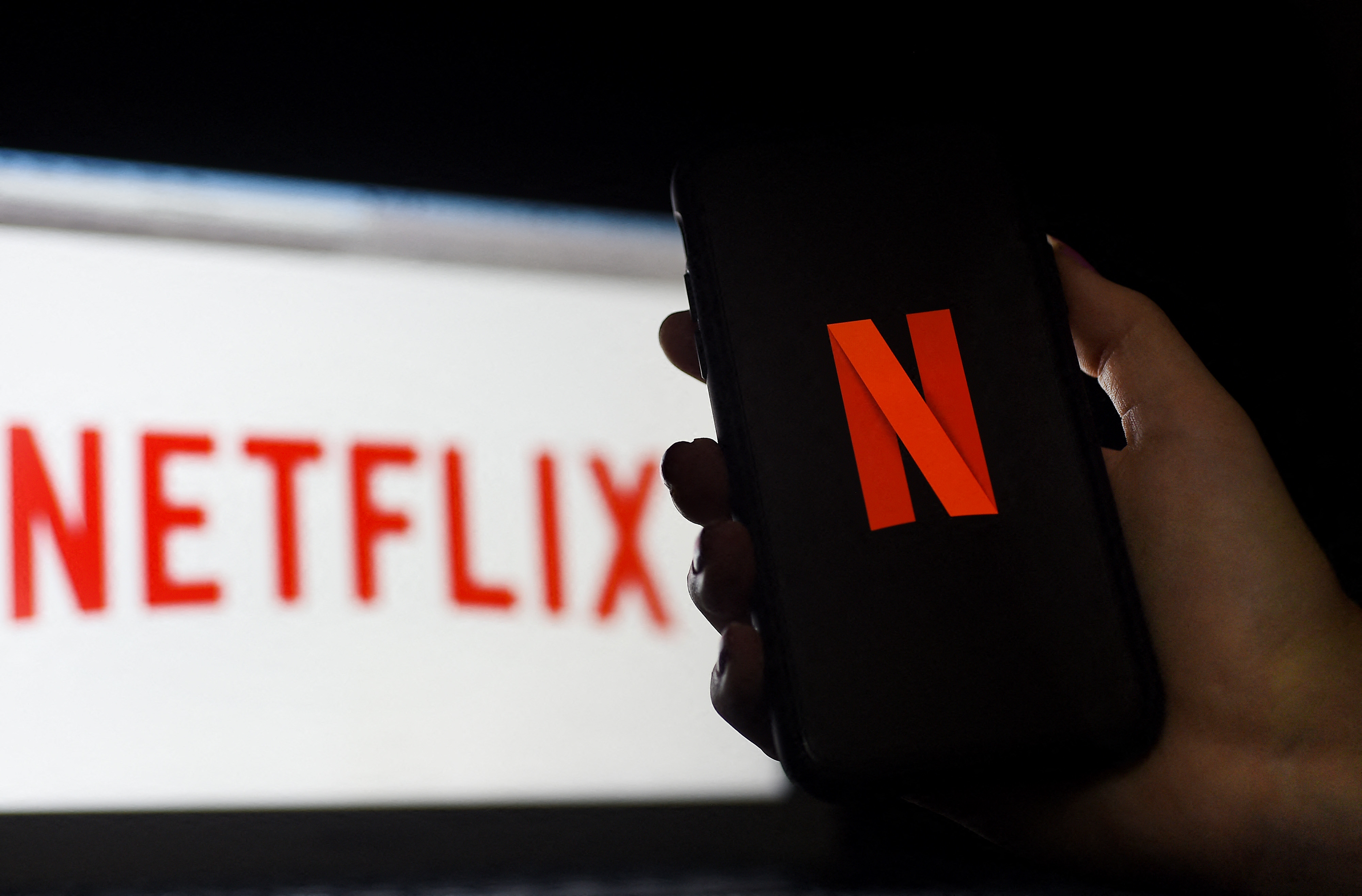 (FILES) In this photo illustration a computer and a mobile phone screen display the Netflix logo on March 31, 2020 in Arlington, Virginia. - Netflix is facing a formidable challenge as it expands into video games to keep the attention of customers in the increasingly competitive world of streaming television. The streaming television leader offered details of its plans to move into games in its latest update confirming cooling growth even as the Silicon Valley giant spins off hit shows. (Photo by Olivier DOULIERY / AFP)