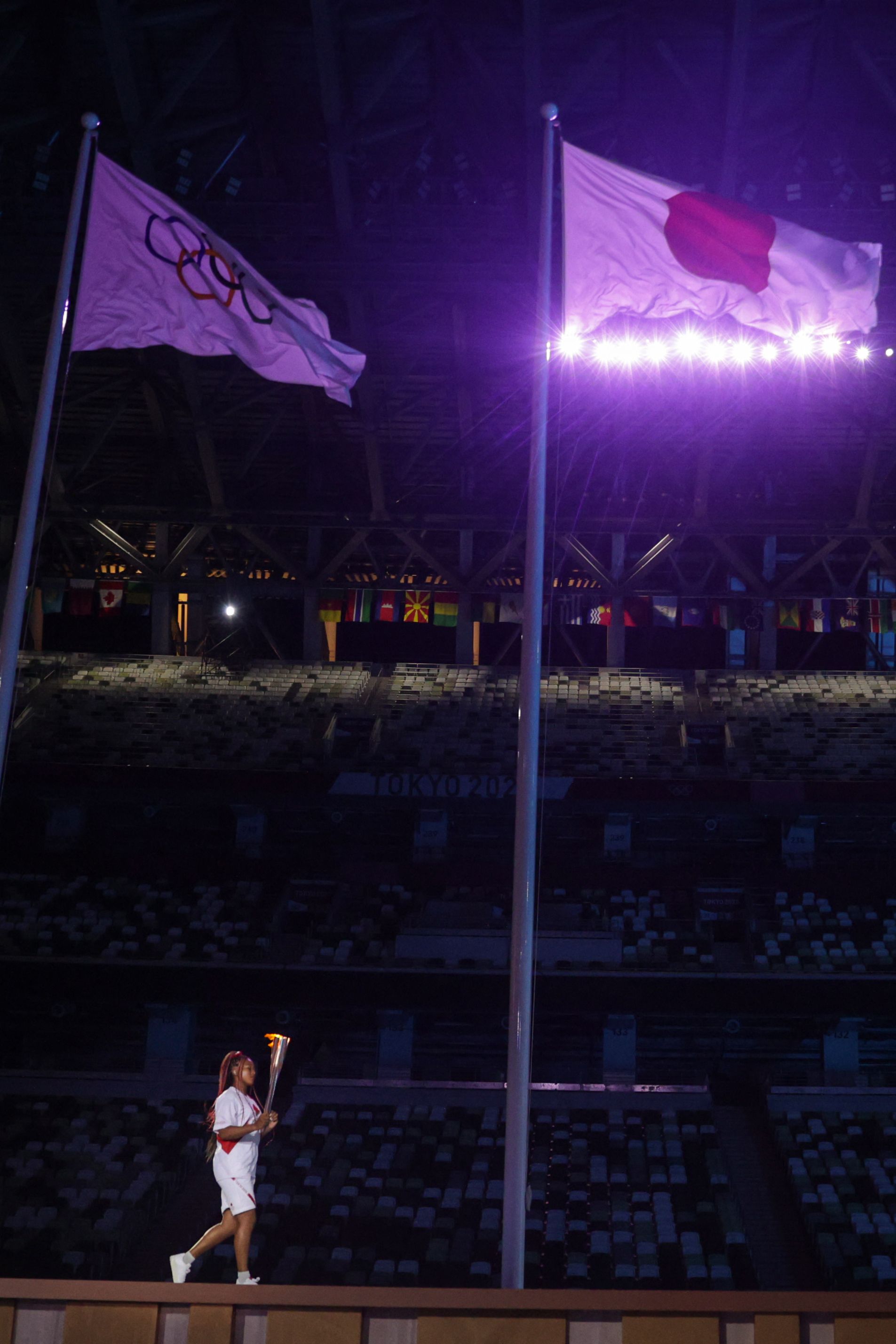 Japan's tennis player Naomi Osaka carries the Olympic Torch before lighting the flame of hope in the Olympic Cauldron during the opening ceremony of the Tokyo 2020 Olympic Games, at the Olympic Stadium, in Tokyo, on July 23, 2021. (Photo by HANNAH MCKAY / POOL / AFP)