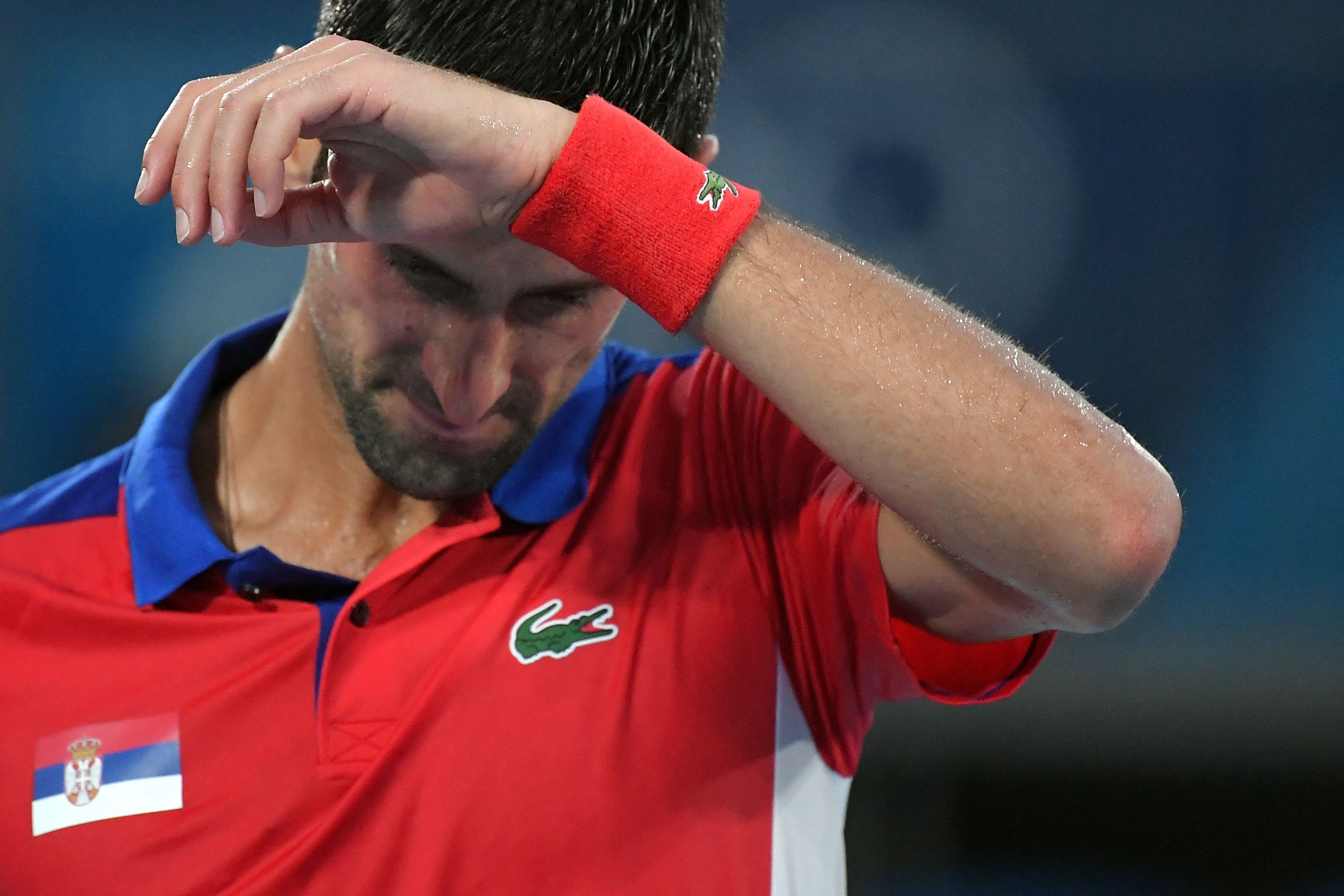 Serbia's Novak Djokovic reacts to being defeated by Germany's Alexander Zverev in their Tokyo 2020 Olympic Games men's singles semifinal tennis match at the Ariake Tennis Park in Tokyo on July 30, 2021. (Photo by Tiziana FABI / AFP)