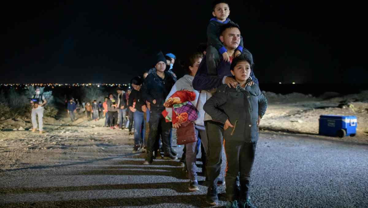 (FILES) In this file photo taken on March 27, 2021 a family of immigrants who arrived illegally across the Rio Grande river from Mexico stand in line at a processing checkpoint before being detained at a holding facility by border patrol agents in the border city of Roma. - US authorities began on July 30, 2021 deporting some migrant families on flights to Central America as part of an expedited system to remove people who arrived without authorization via Mexico. (Photo by Ed JONES / AFP)