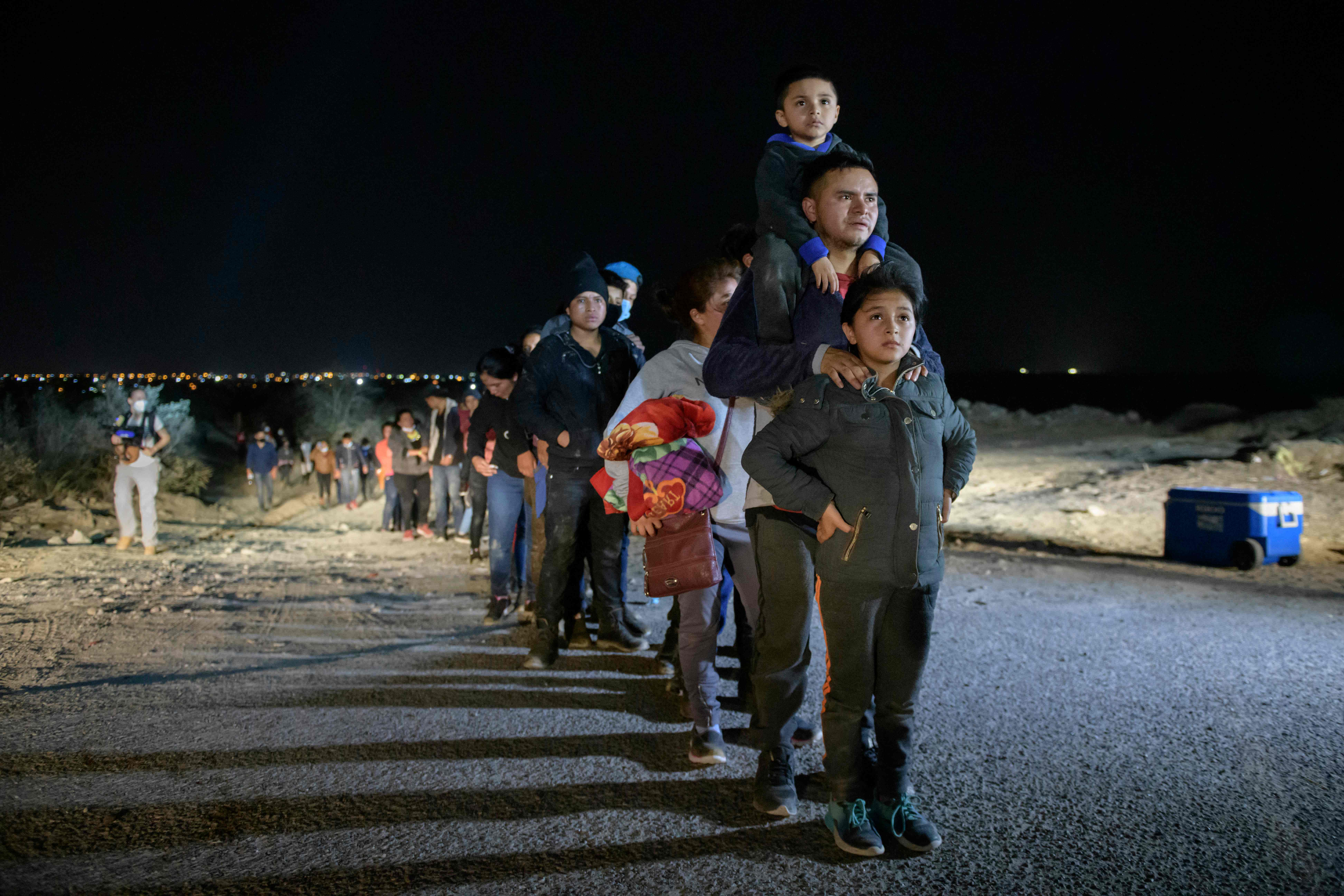 Una familia de migrantes que llegó a EE. UU. de forma ilegal a través del río Grande desde México hace fila antes de su traslado a un centro de detención de la Patrulla Fronteriza. (Foto Prensa Libre: AFP)