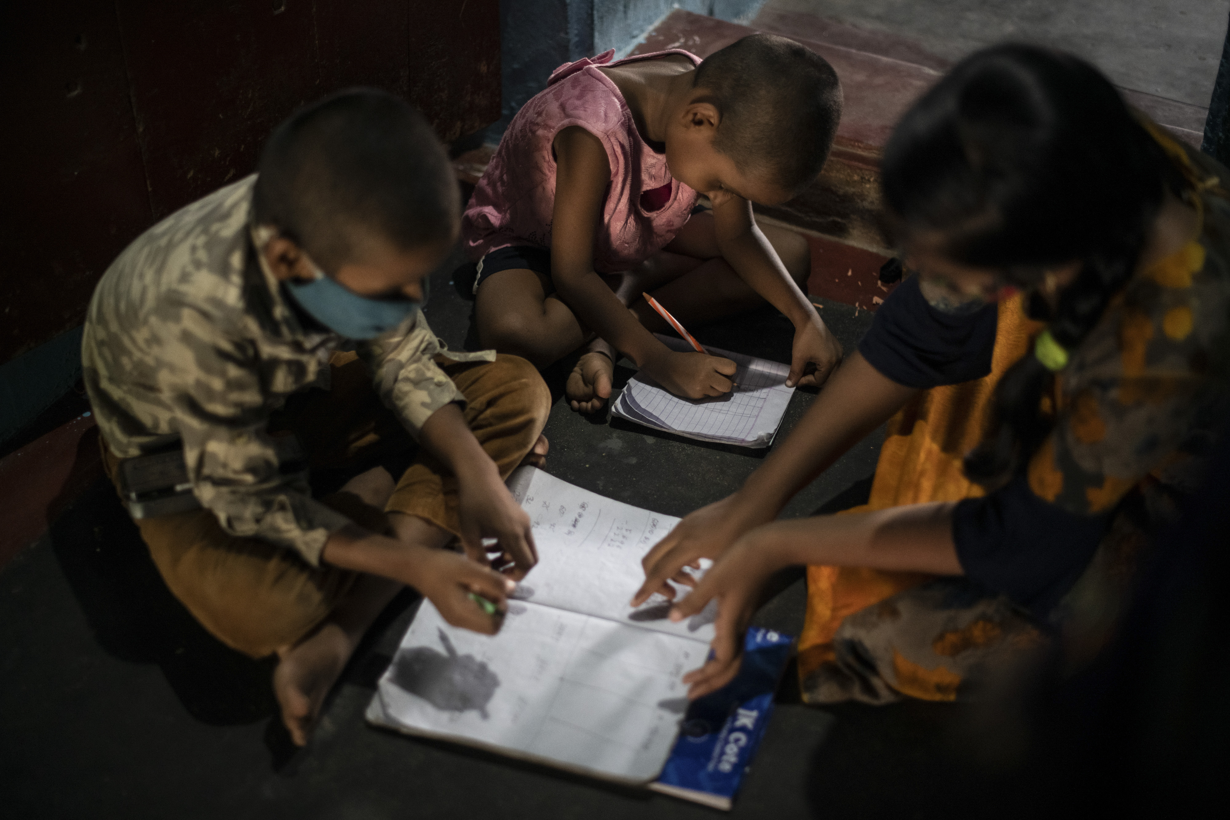G. Sonali Reddy, que quedó huérfana junto a sus hermanos tras la muerte de sus padres a causa del COVID-19, ayuda a sus hermanos a leer y escribir en Pattapur, India, el 20 de junio de 2021. (Foto Prensa Libre: Rebecca Conway/The New York Times)