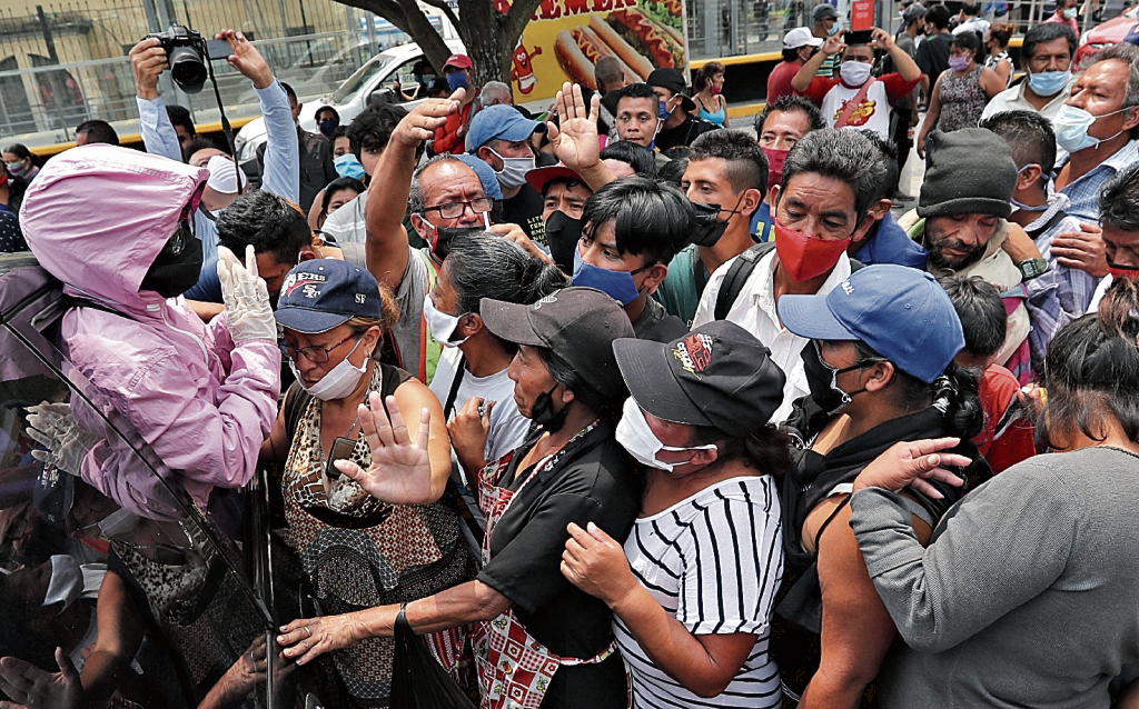 Vendedores informales corren al ver que una persona llega en su vehículo a dejarles unos panes para el desayuno pero se aglomeraron tanto las personas que llegaron decidieron irse por que no hacia caso para recibir sus panes esto en el parque de la constitución la pandemia del Coronavirus vino a desestabilizar la economía . Fotografía. Erick Avila: 25/04/2020