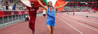 El catarí Mutaz Essa Barshim (I) y el italiano Gianmarco Tamberi celebran en el Estadio Olímpico de Tokio la medalla de oro que ganaron en salto alto. Foto Prensa Libre: AFP.