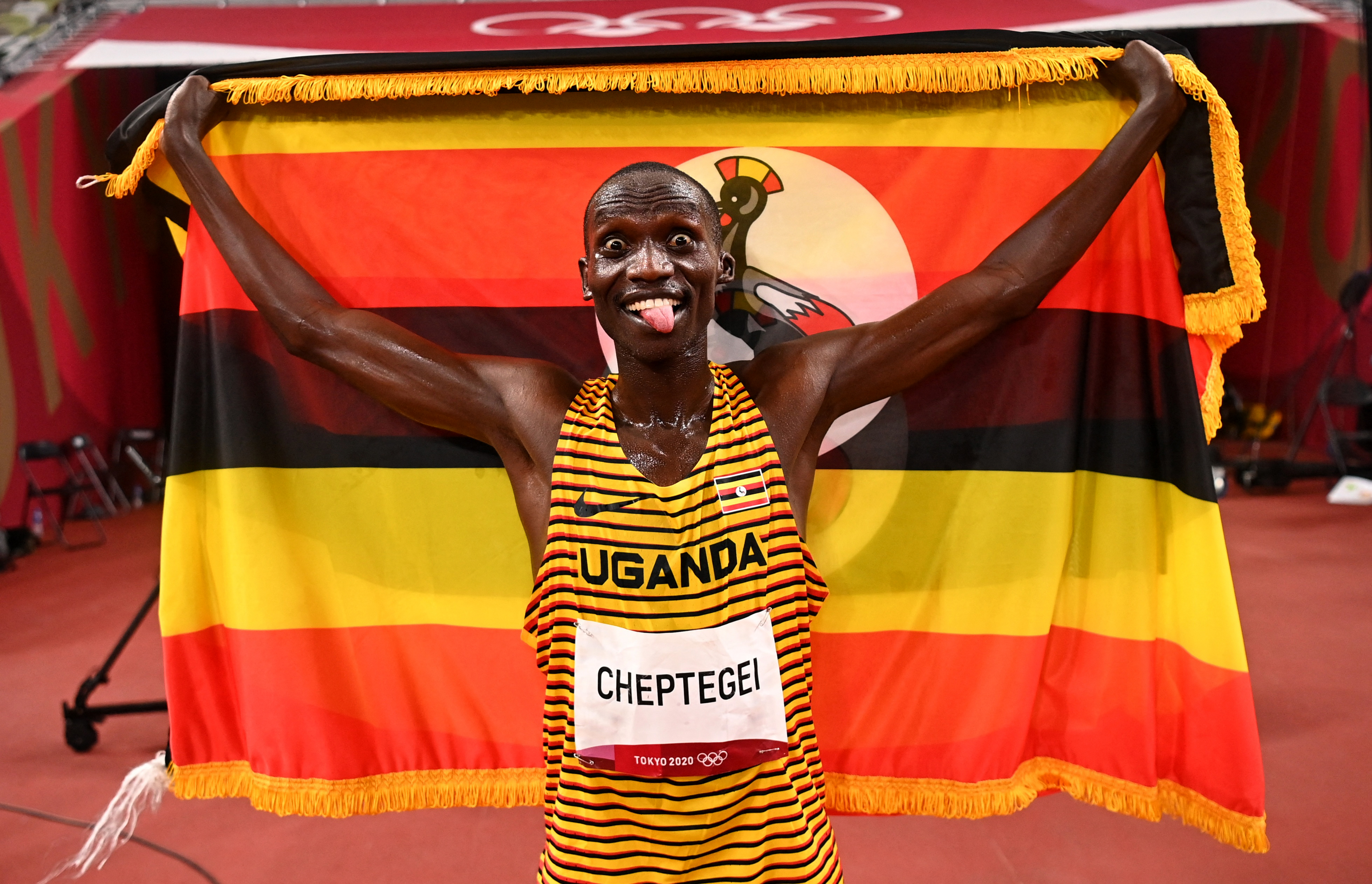 Joshua Cheptegei de Uganda con la bandera de su país la victoria en los 5000m que le dan su primera medalla de oro olímpica. Foto Prensa Libre: AFP.