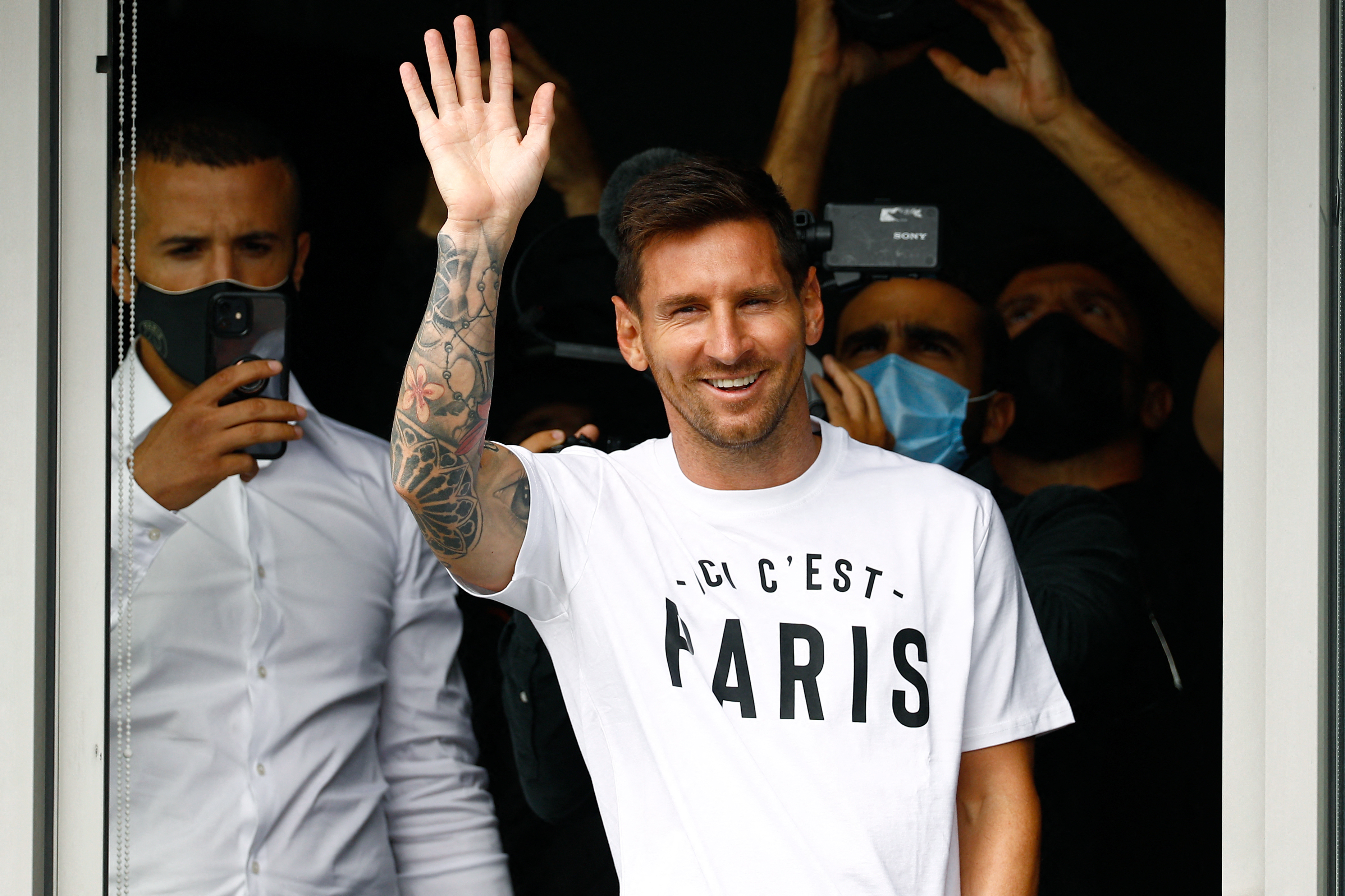 Argentinian football player Lionel Messi waves to supporters from a window after he landed on August 10, 2021 at Le Bourget airport, north of Paris, as Paris Saint-Germain look to complete the 34-year-old signing following his departure from Barcelona, the club he has represented for the entirety of his 17-year professional career so far. - Asked by reporters at Barcelona's El Prat airport if the Argentine star would later on sign with the French club, Jorge Messi, the father and player's agent, said: 